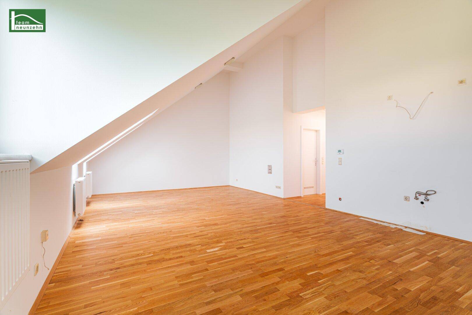 Weitläufiges Dachgeschosszimmer mit Holzboden und schrägen Wänden, bietet viel Potenzial für individuelle Gestaltung.