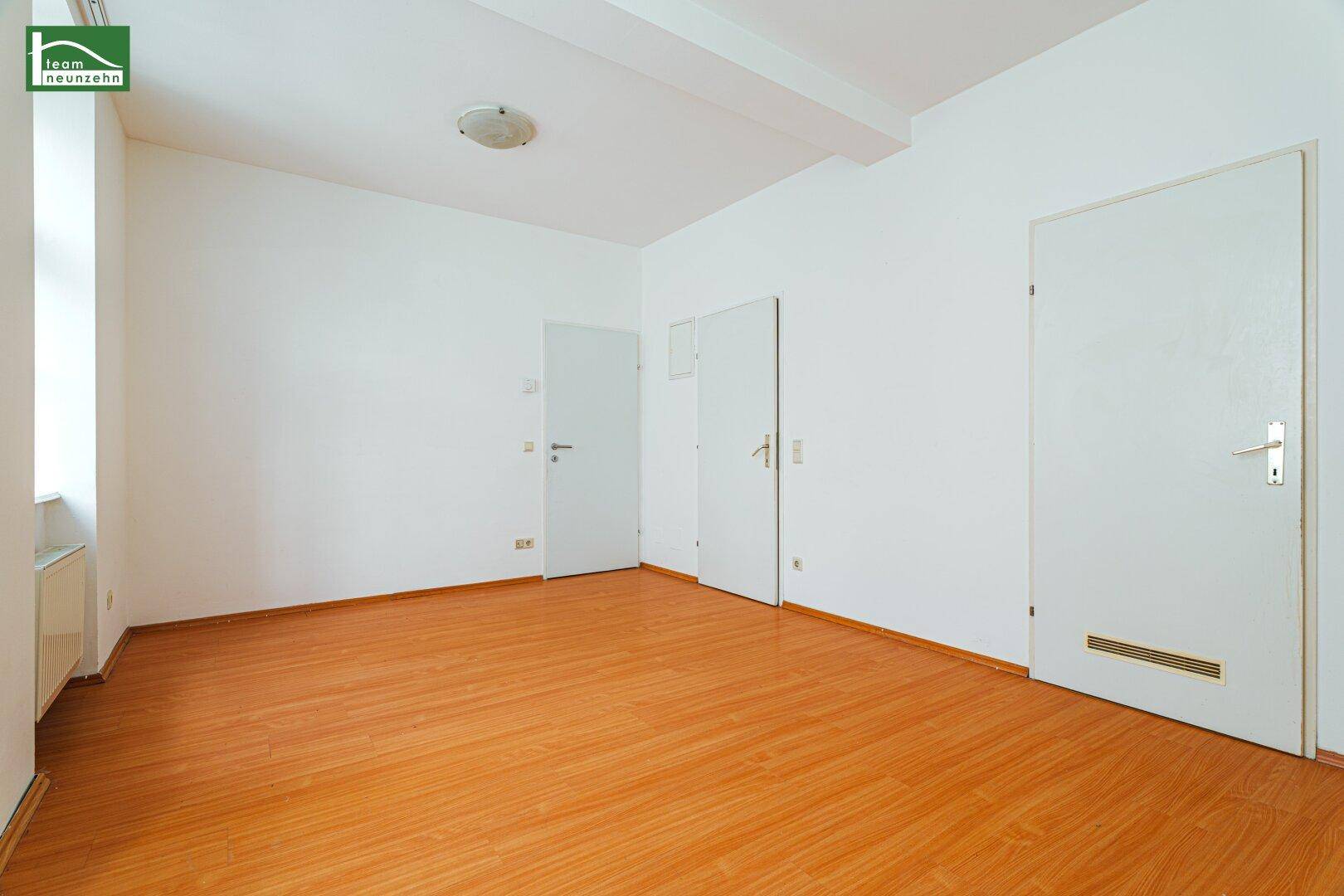 Geräumiges Zimmer mit hellem Laminatboden und mehreren Türen, bietet flexible Nutzungsmöglichkeiten.