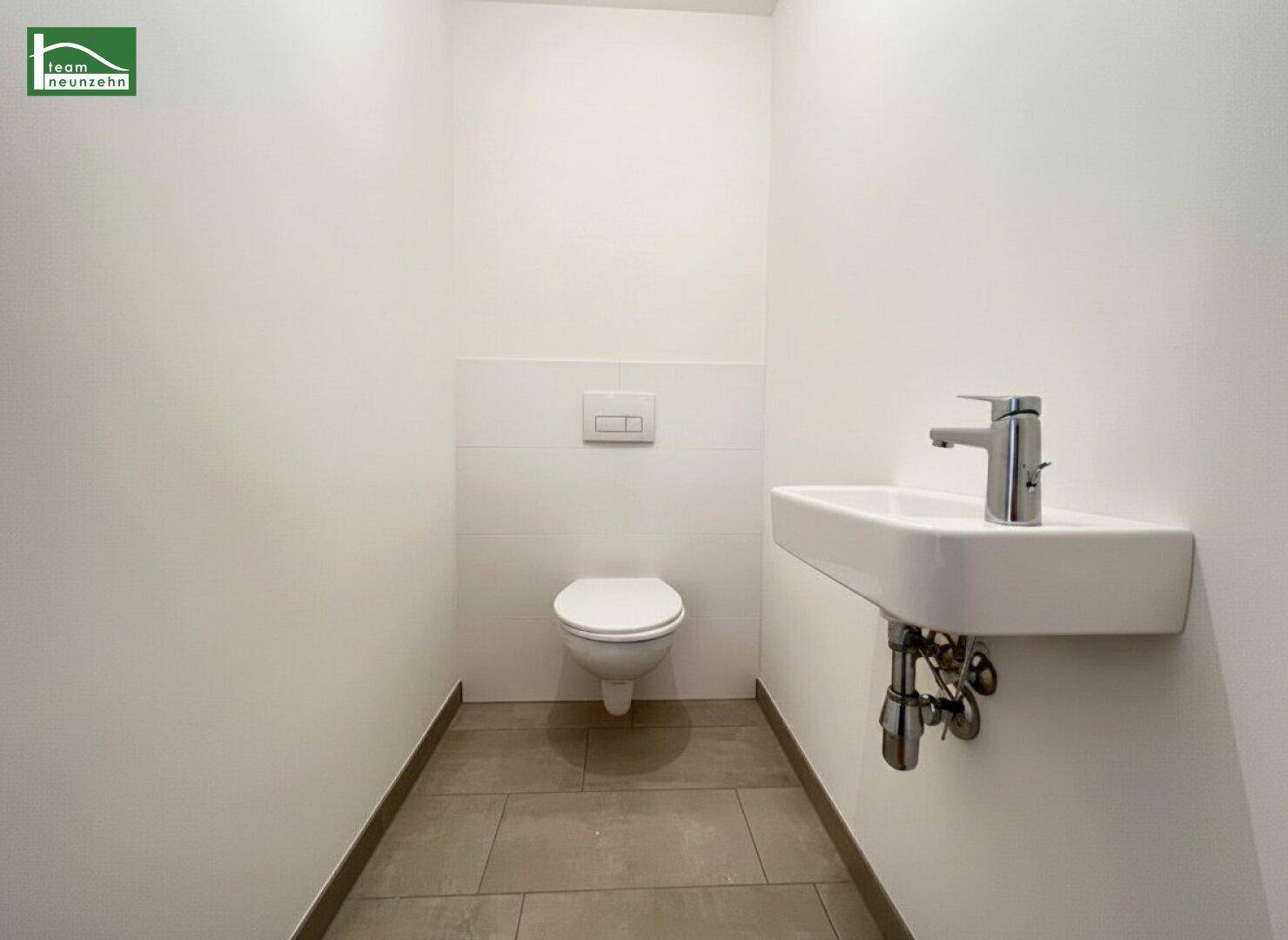 Separates Gäste-WC mit wandhängender Toilette und modernem Waschbecken.