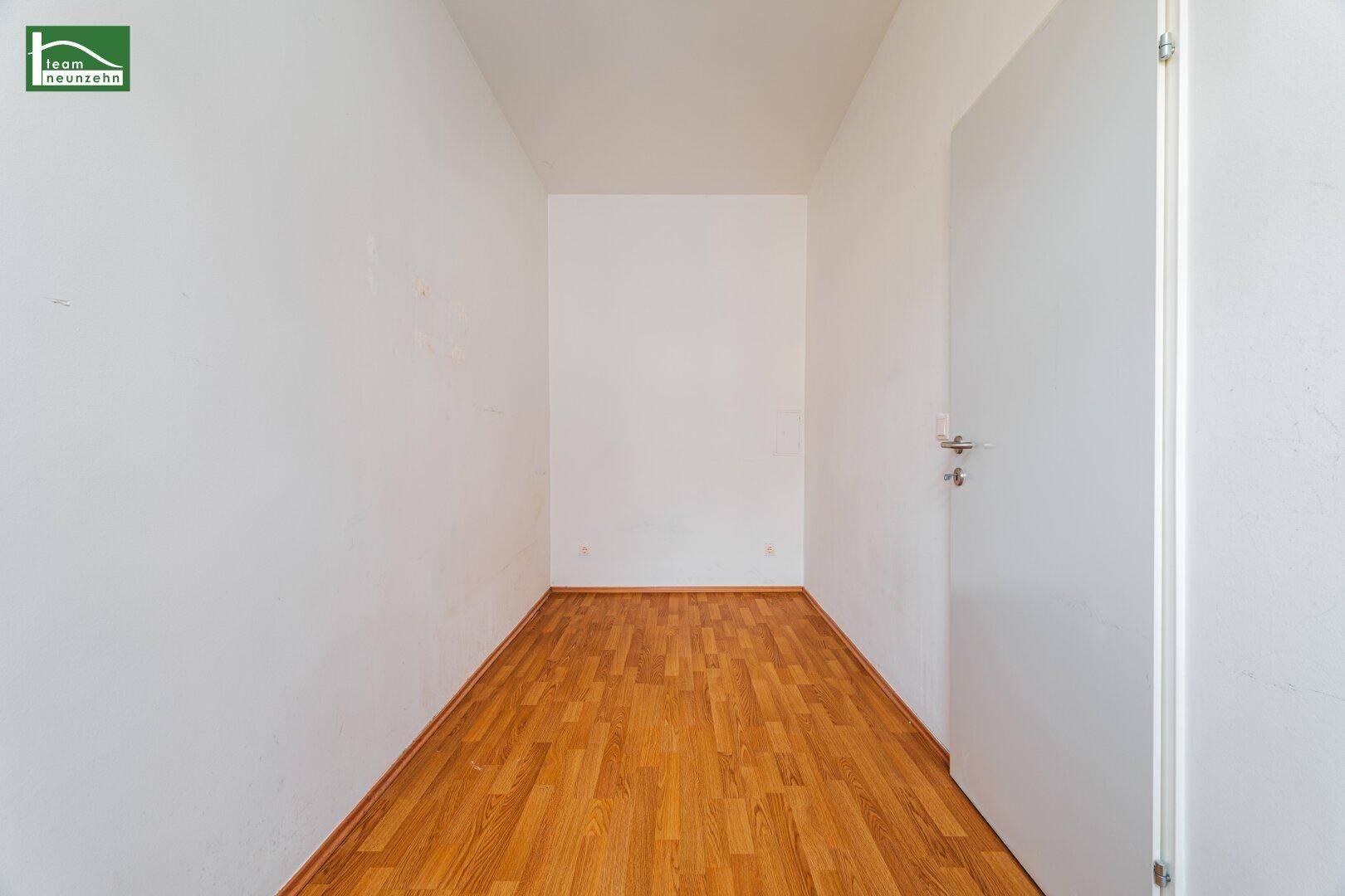 Langer, schmaler Raum mit Holzboden, geeignet als Abstellraum oder begehbarer Kleiderschrank.