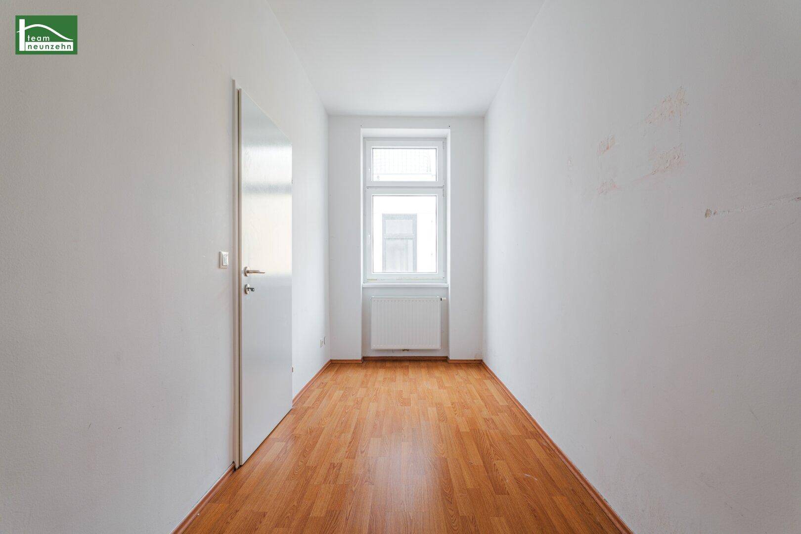 Schmaler, heller Raum mit Holzboden und einem Fenster, ideal als Schlaf- oder Arbeitszimmer.