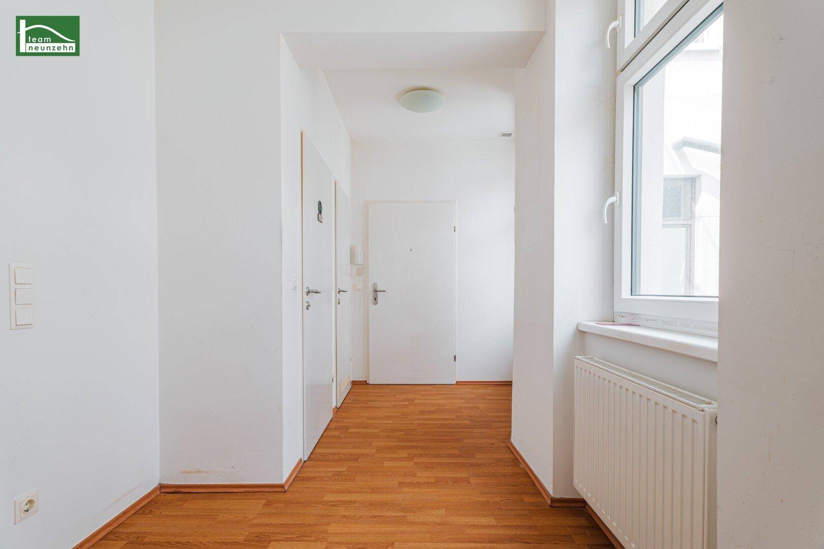 Geräumiger Flur mit Holzboden, Fenster und Zugang zu verschiedenen Räumen der Wohnung.