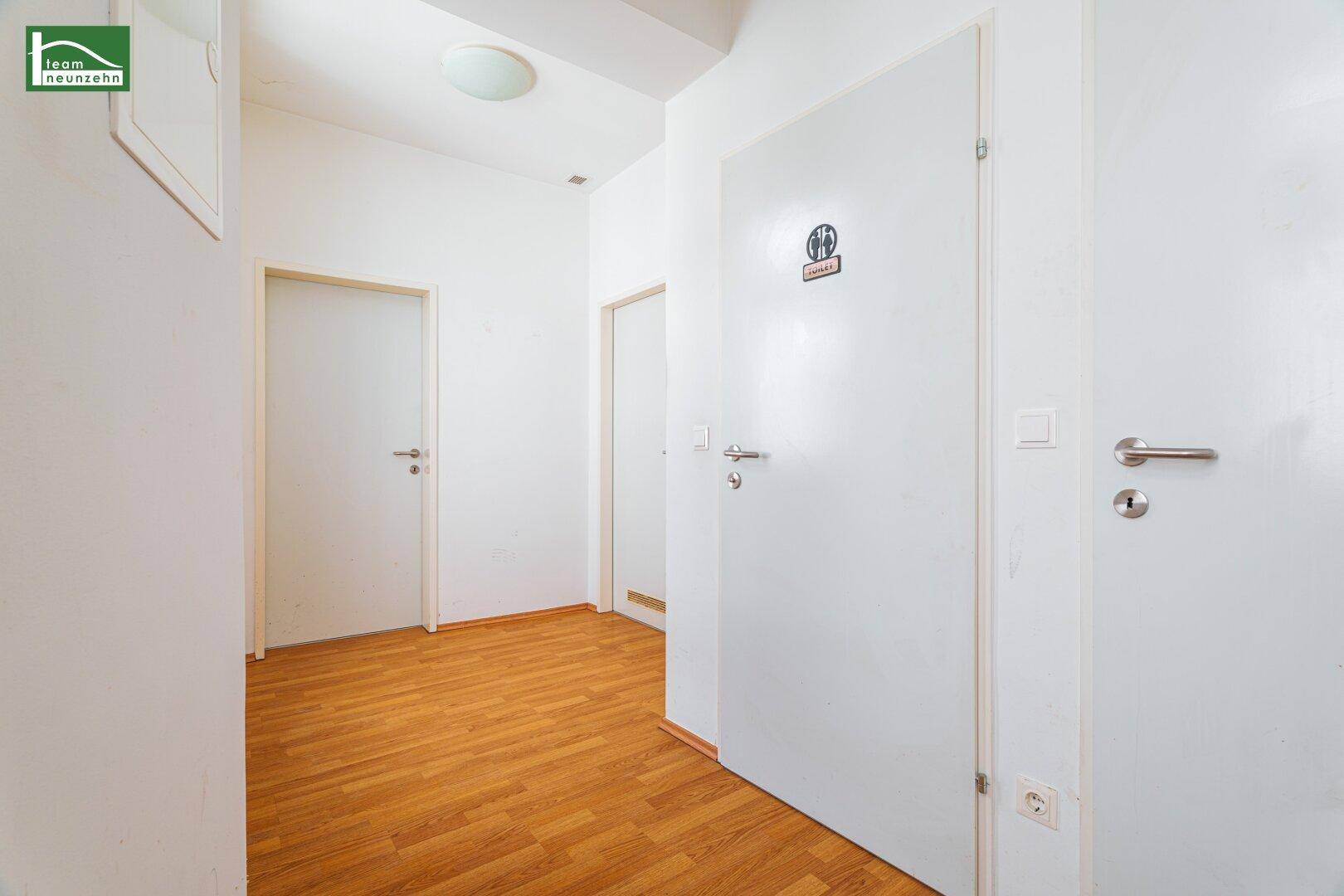 Heller Flur mit Holzboden und mehreren weißen Türen, die zu den Zimmern führen.