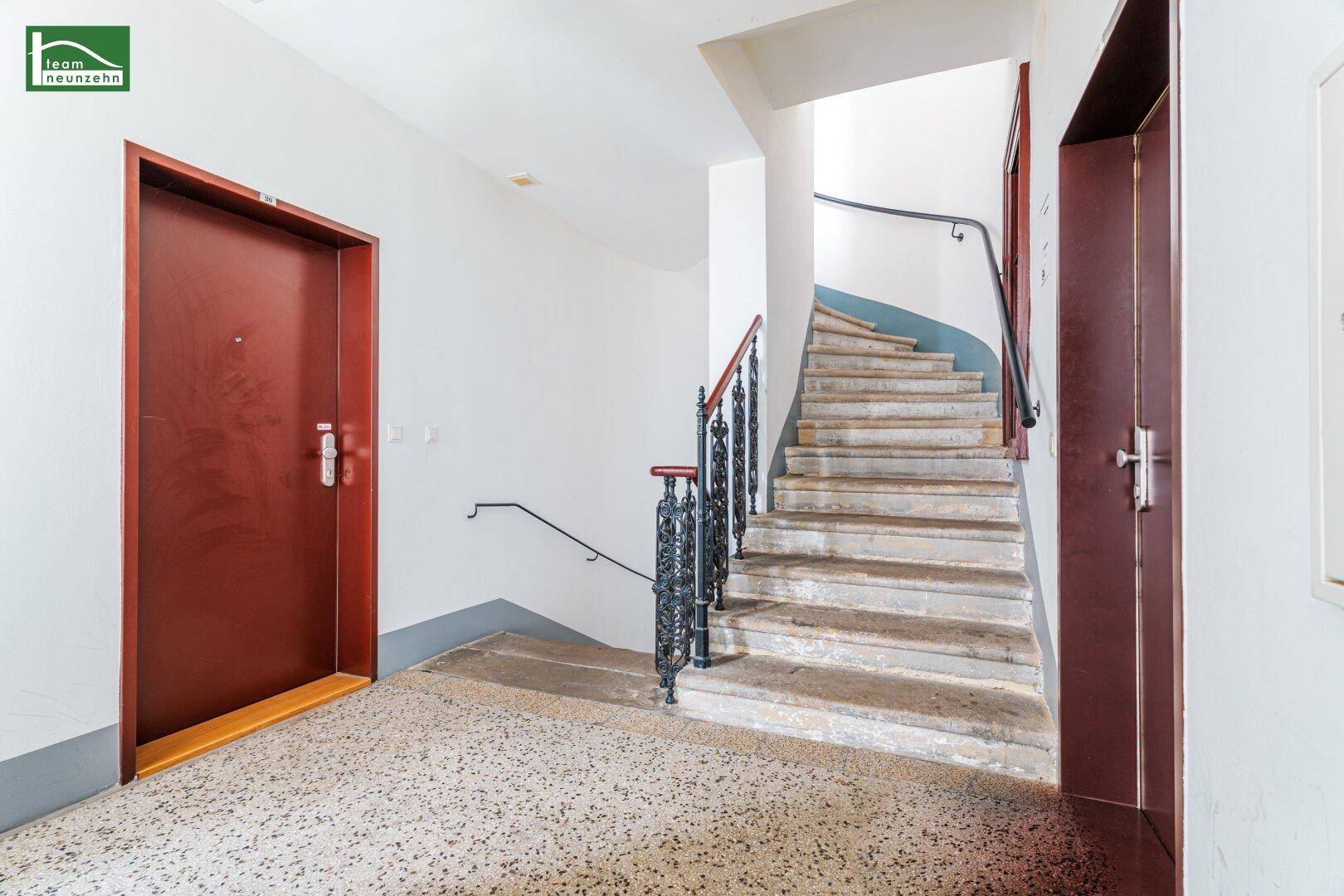 Historisches Treppenhaus mit Steinstufen und schmiedeeisernem Geländer in einem Altbau.