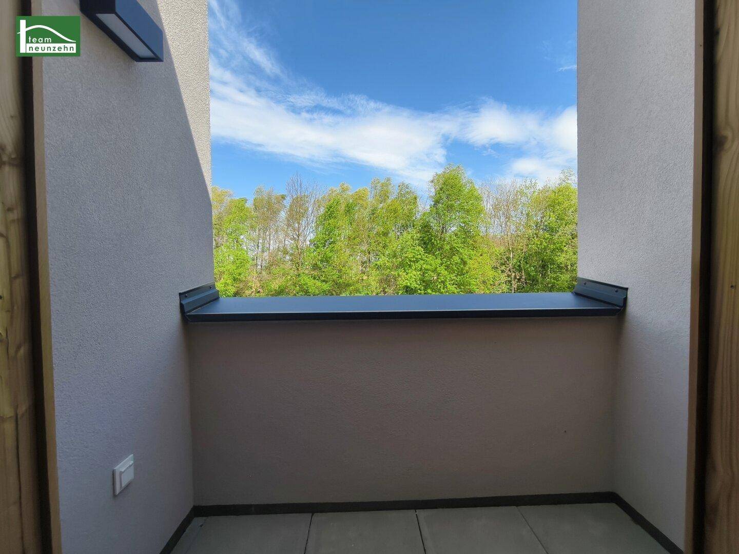 Heller Balkon mit klaren Linien und weitem Blick in die umgebende Natur an einem sonnigen Tag.