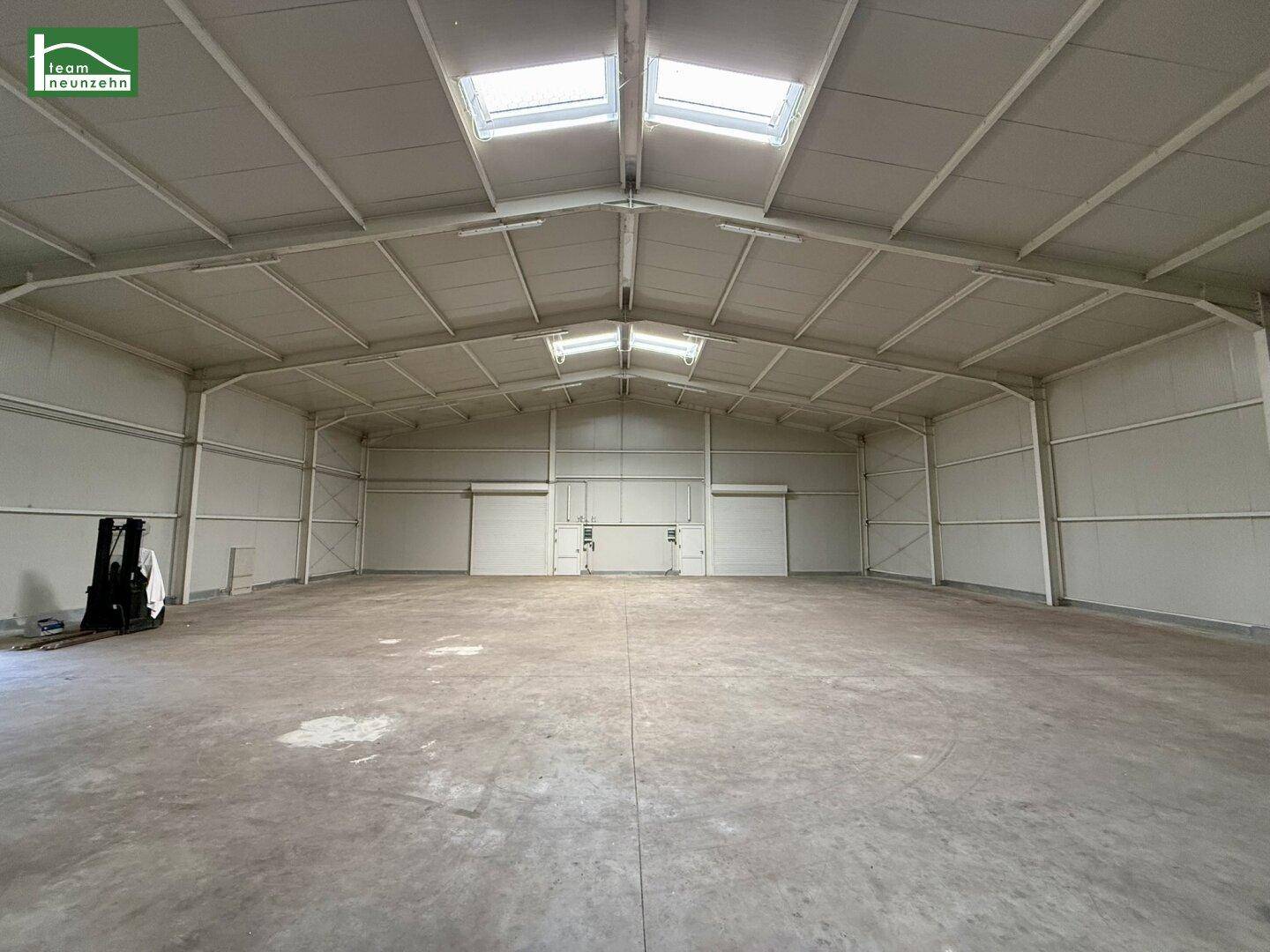Weitläufige Lagerhalle mit hohen Decken, Oberlichtern und sauberem Betonboden, bereit zur Nutzung.