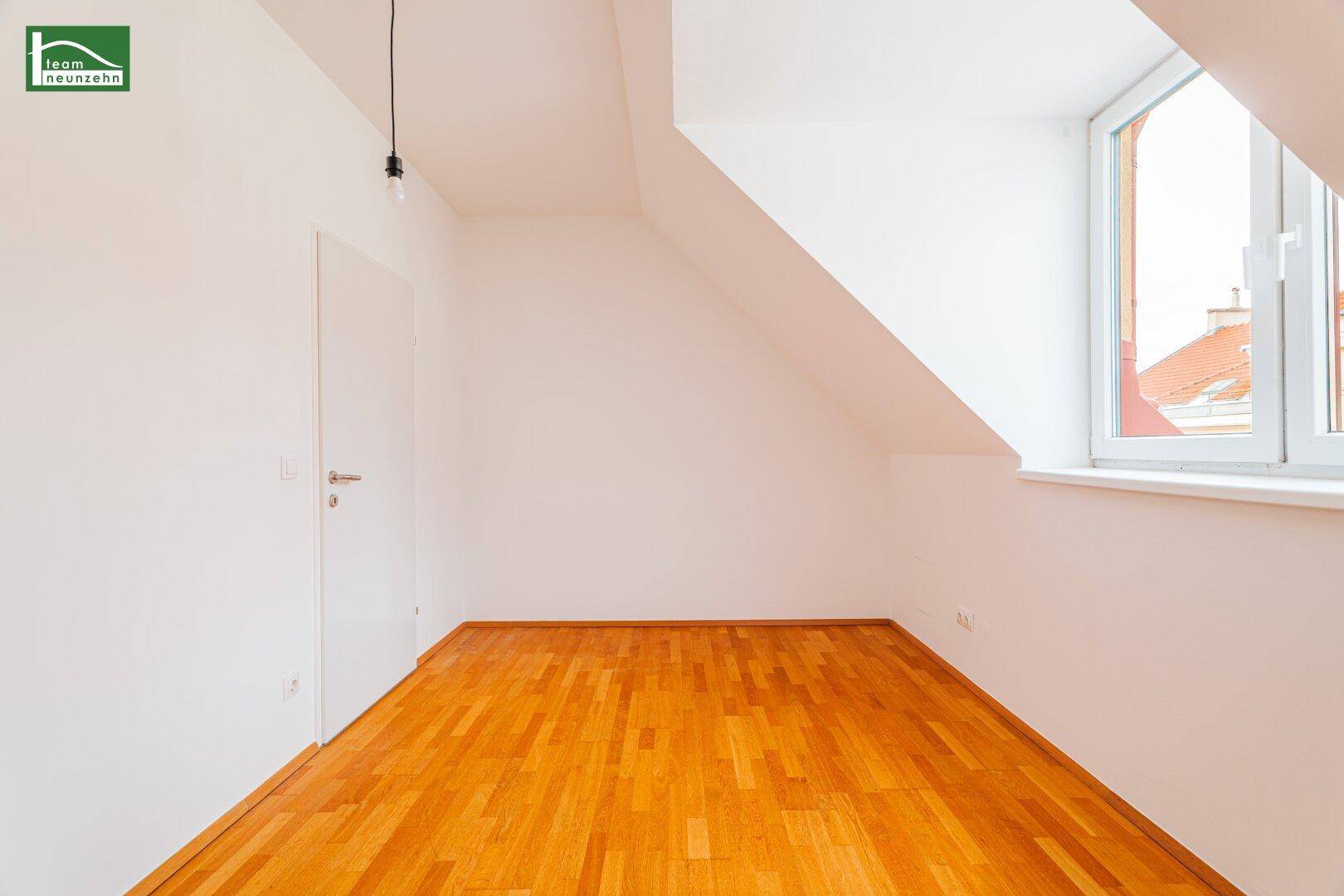 Helles Zimmer im Dachgeschoss mit Holzboden und schrägen Wänden, ideal als Schlafzimmer.
