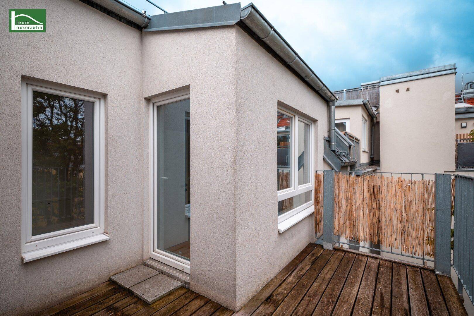 Außenansicht des Gebäudes mit Holzbalkon und Fenstern, die viel Licht hereinlassen.