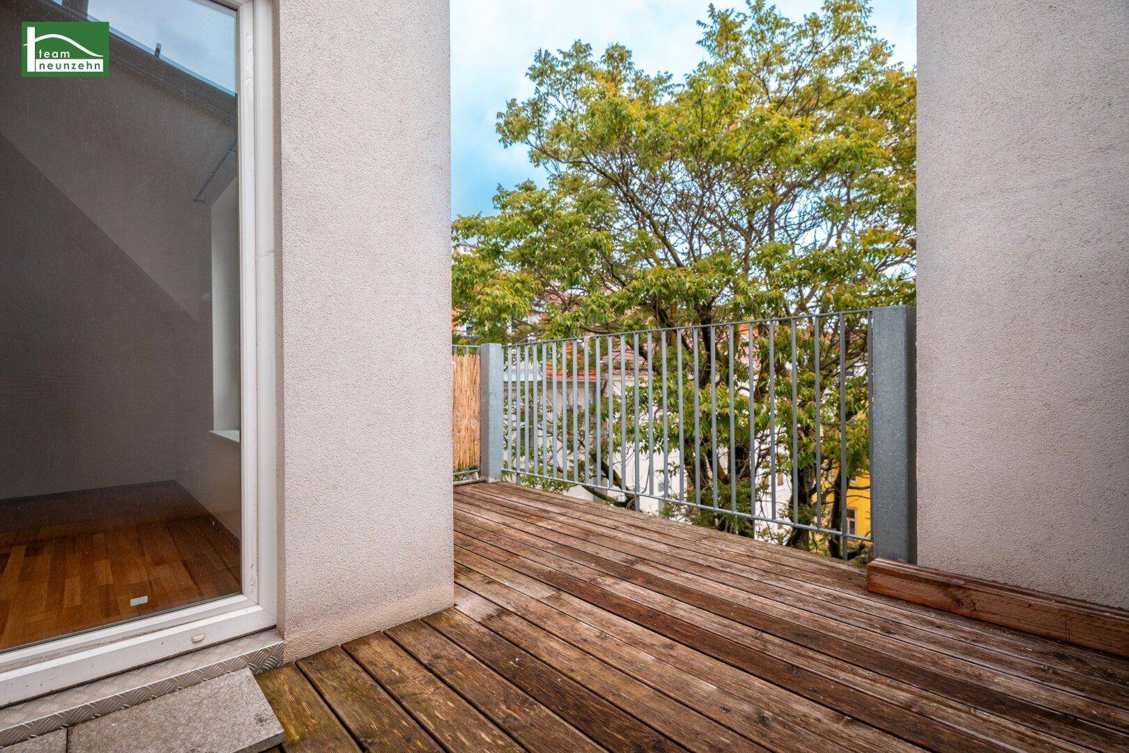 Heller Holzbalkon mit Metallgeländer und Blick ins Grüne, ideal zum Entspannen im Freien.