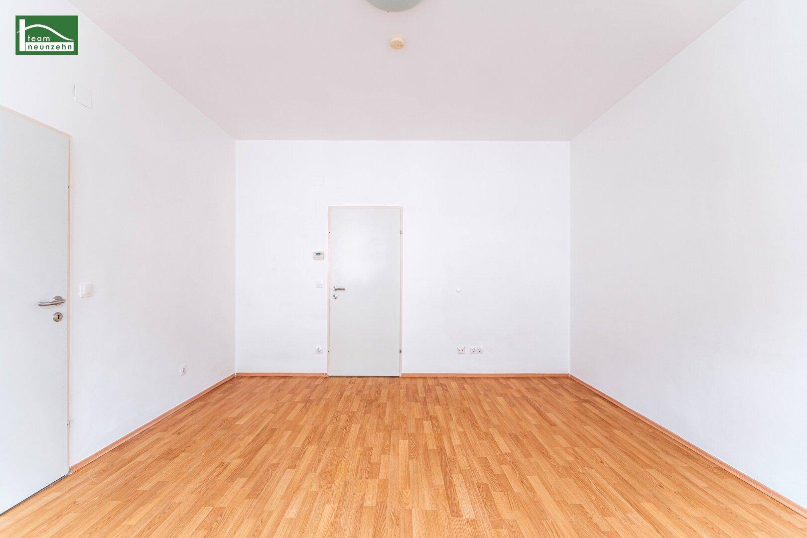Geräumiges Zimmer mit Holzboden und weißen Wänden, bietet vielseitige Nutzungsmöglichkeiten.