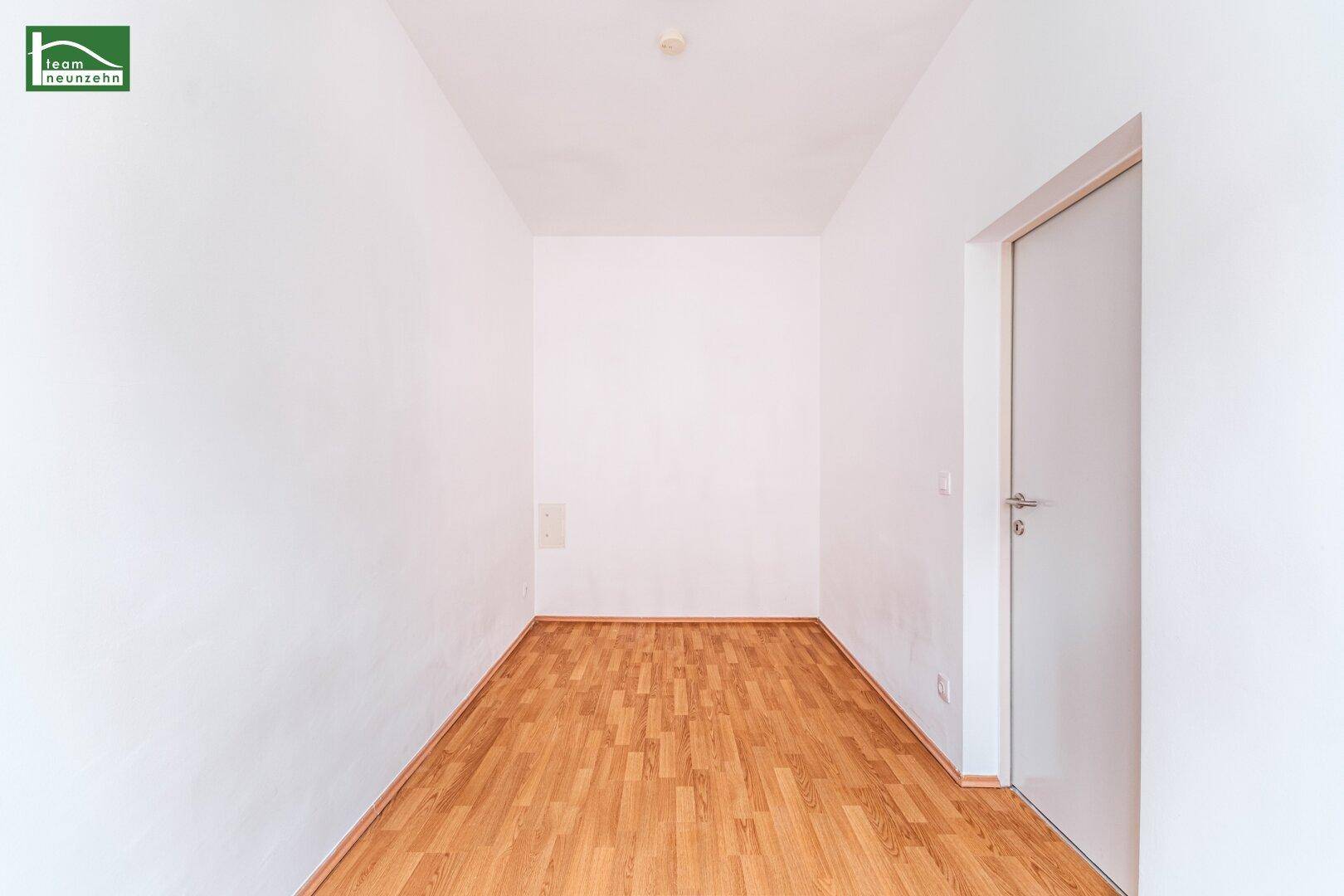 Schmaler Flur mit hellem Holzboden und weißen Wänden, verbindet verschiedene Bereiche der Wohnung.