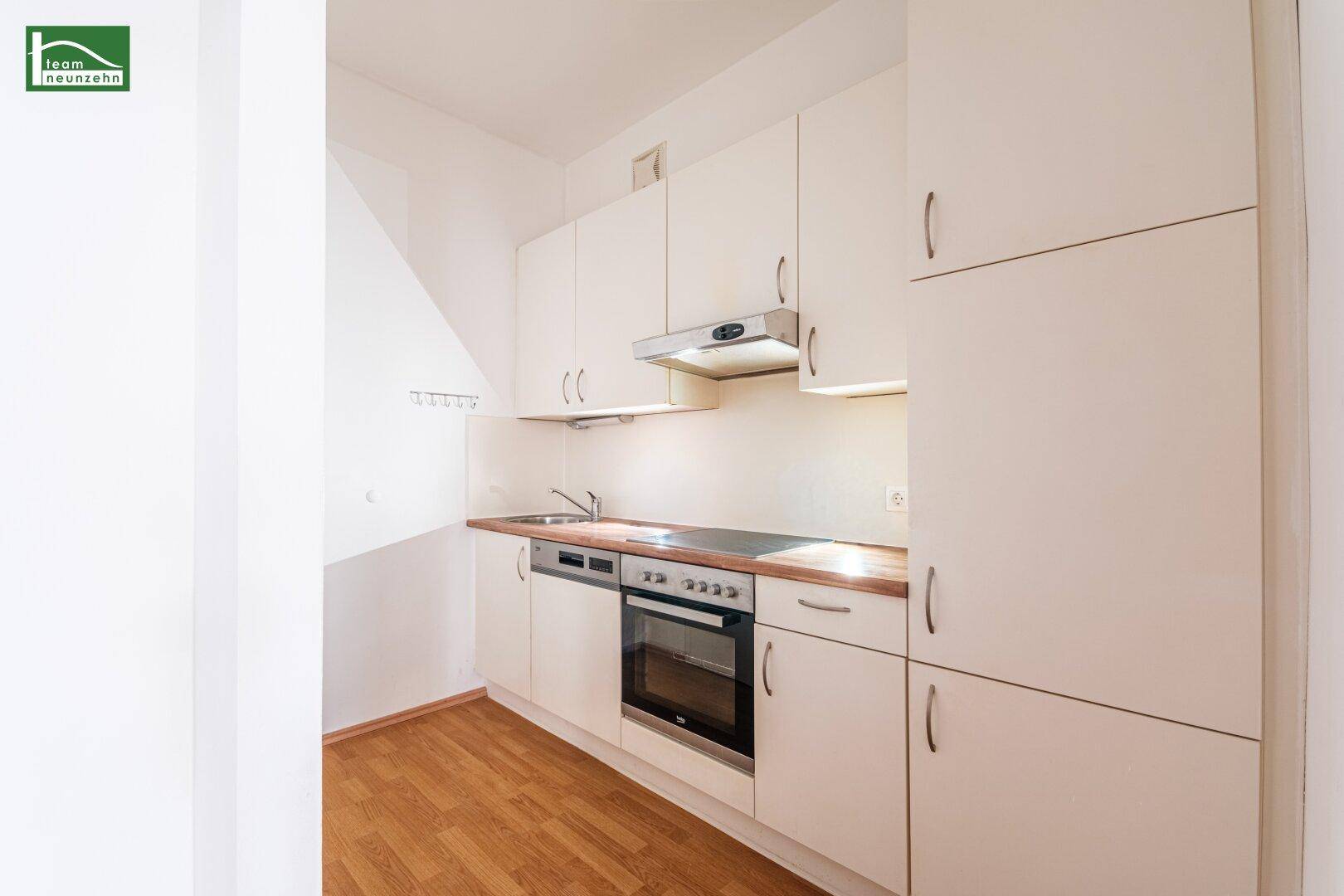 Funktionale Küche mit weißen Schränken, Holzarbeitsplatte und integrierten Geräten, bereit zum Kochen.