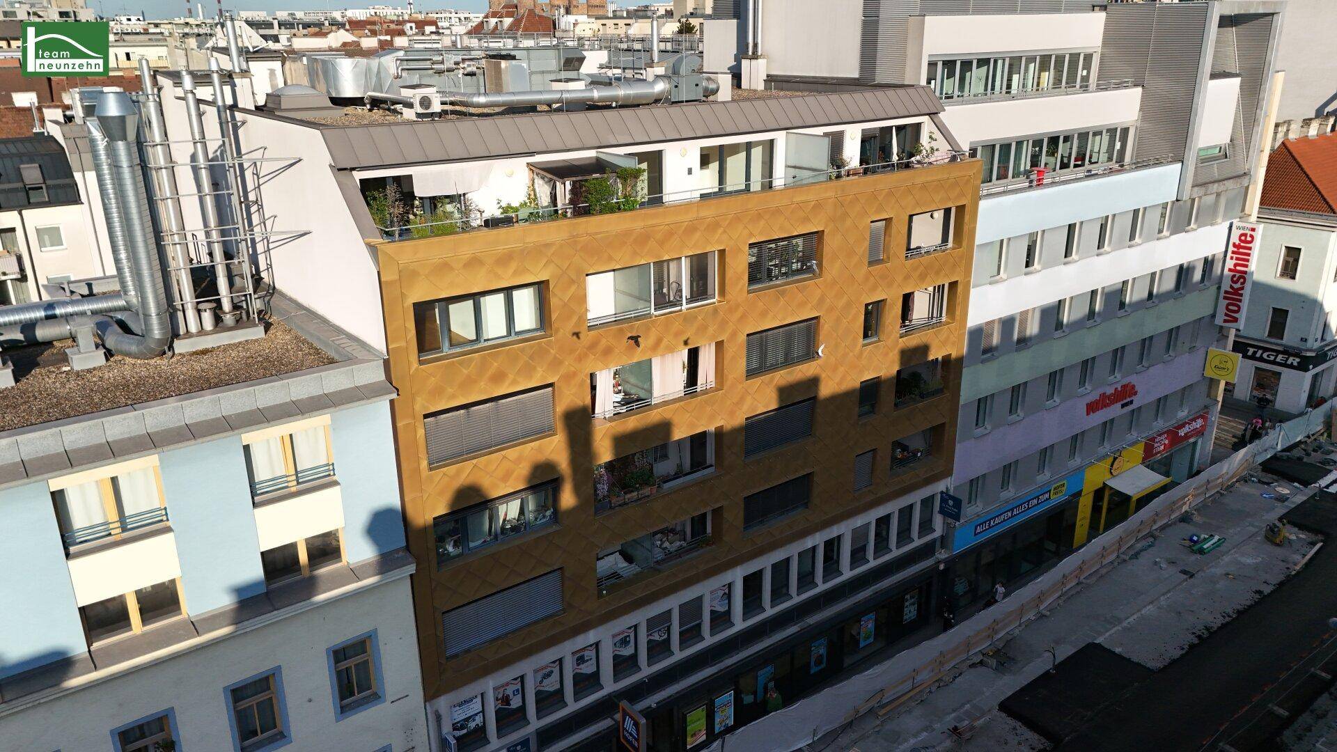 Panoramablick auf eine moderne Gebäudefassade mit goldfarbenen Akzenten in urbaner Umgebung.