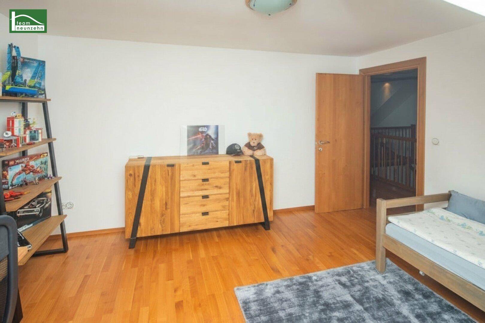 Kinderzimmer mit Holzboden, modernem Holzschrank und schräger Decke, ideal für junge Bewohner.