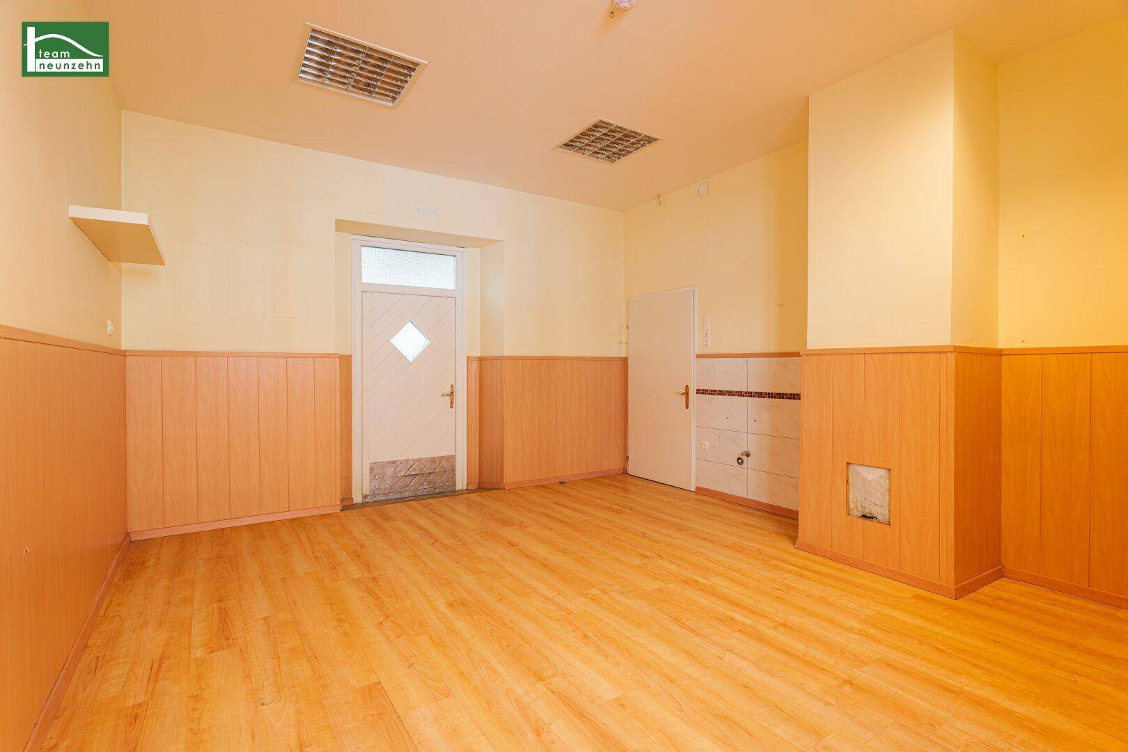 Geräumiger Innenraum mit Laminatboden und Holzpaneelen, mit Zugang zu weiteren Bereichen.