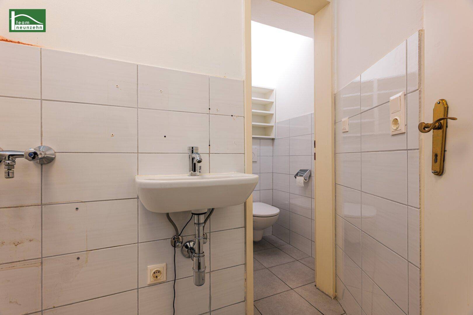 Kleiner Waschraum mit Waschbecken und Zugang zu einer separaten Toilette.