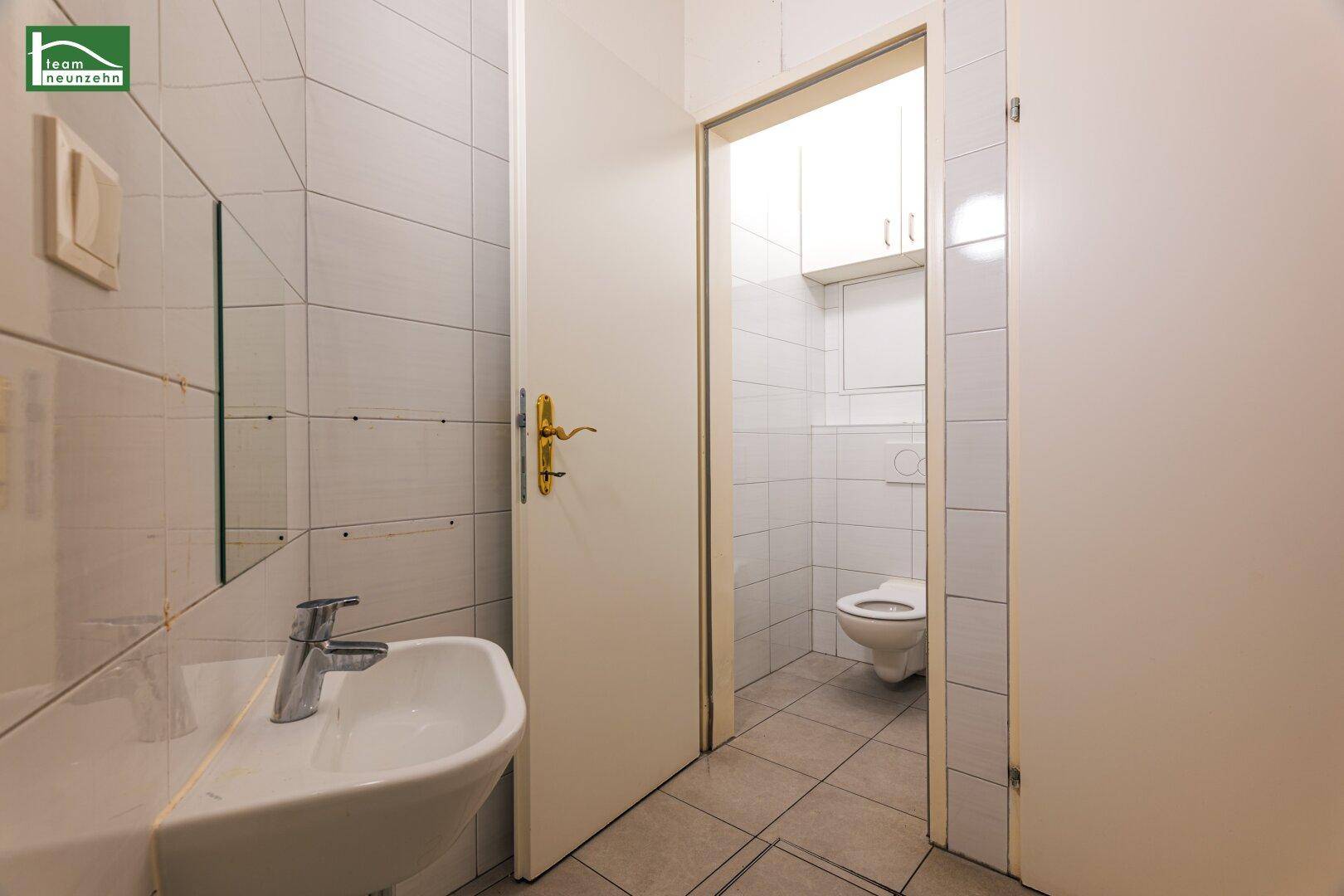 Waschraum mit Waschbecken und Spiegel, bietet Zugang zu einer separaten Toilette.