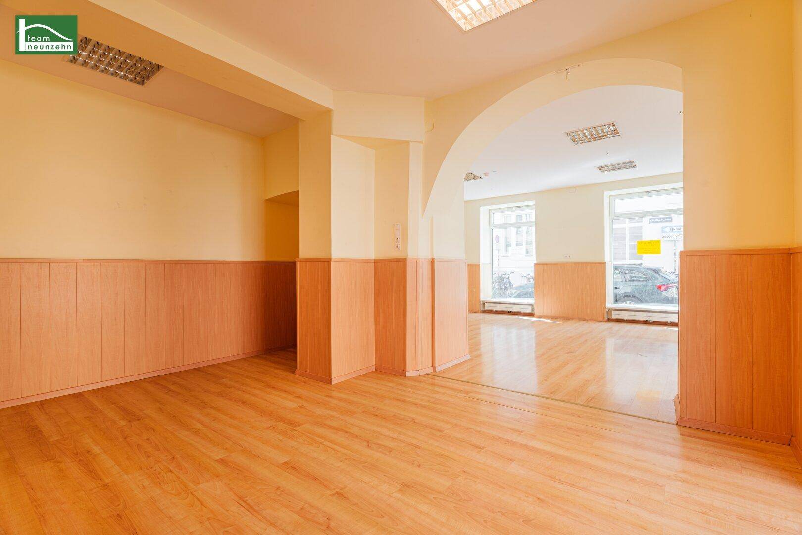 Offener, heller Bereich mit Laminatboden und Holzwänden, mit Blick auf die Straße.