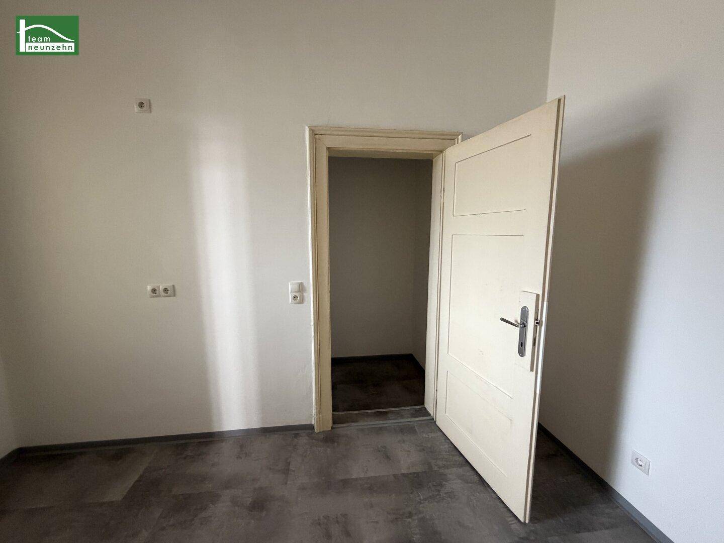 Leerer Raum mit dunklem Vinylboden und offener Tür, geeignet als Abstellkammer.