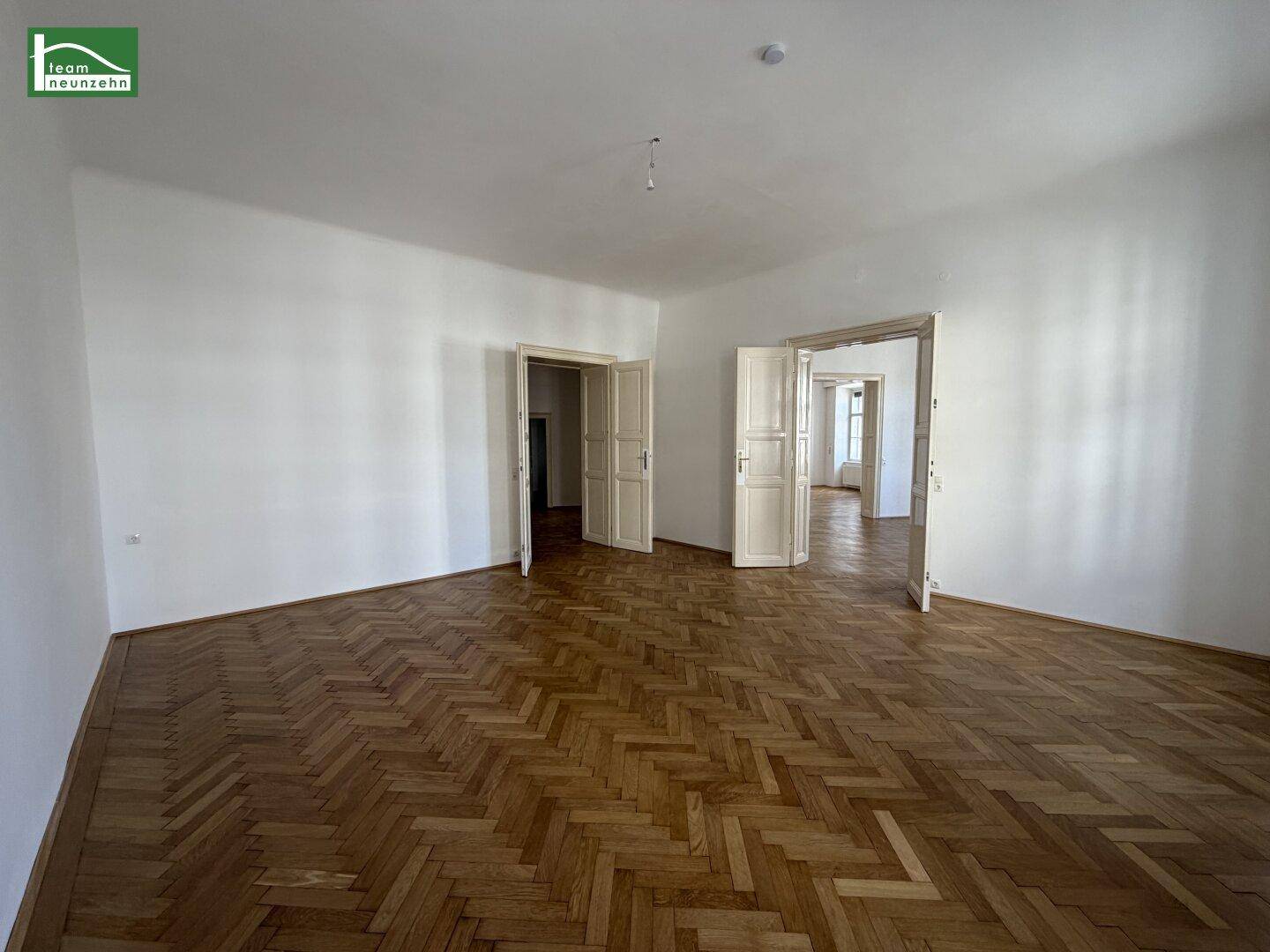 Geräumiger Flur mit Fischgrätparkett und hohen Türen, der mehrere Zimmer verbindet.