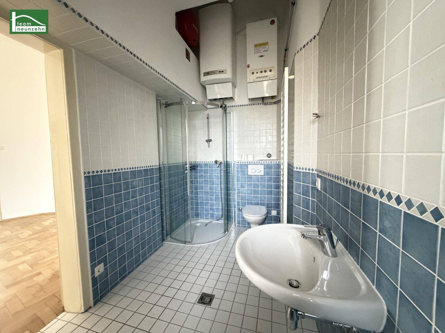 Badezimmer mit blauen und weißen Fliesen, Dusche und WC, funktional ausgestattet.