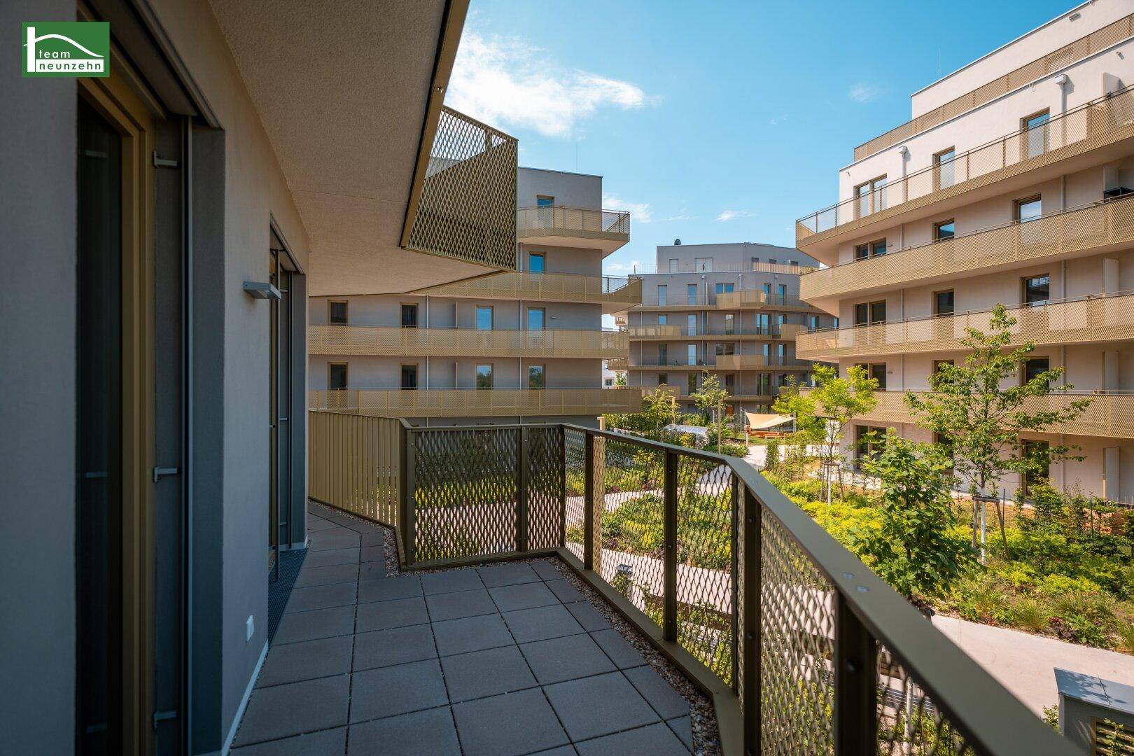 Heller Balkon mit Blick auf die moderne Wohnanlage und die gepflegten Grünflächen.
