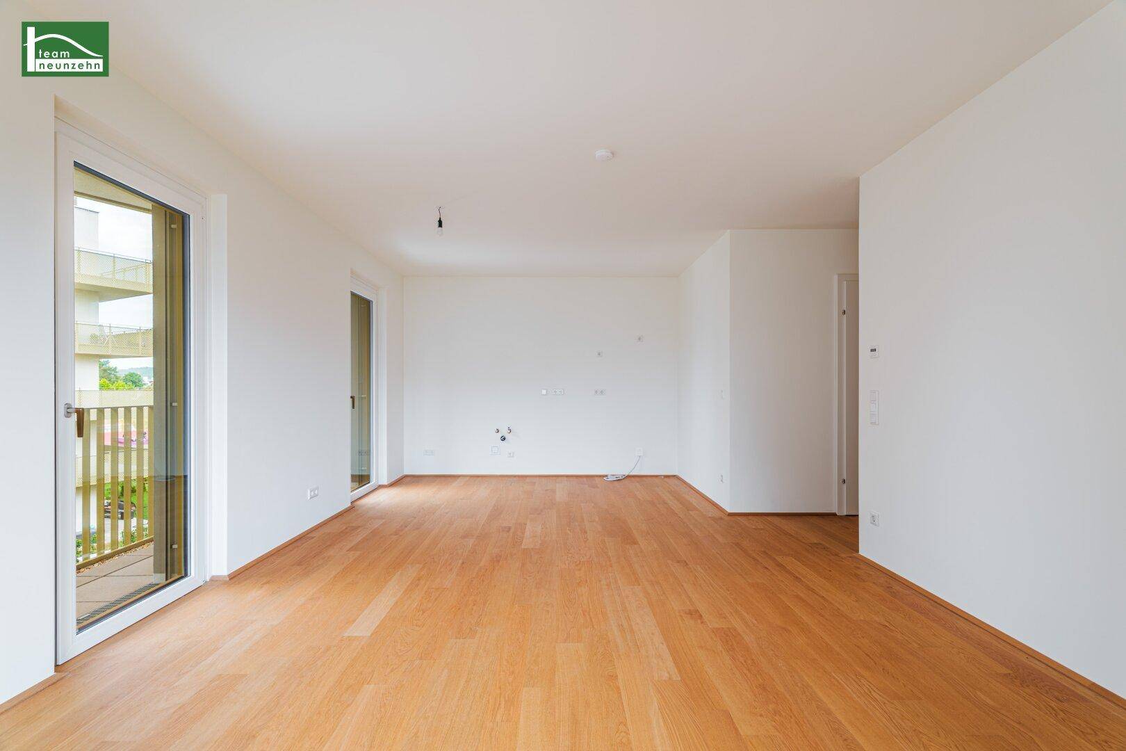 Geräumiges, helles Wohnzimmer mit Parkettboden und Zugang zu einem Balkon.