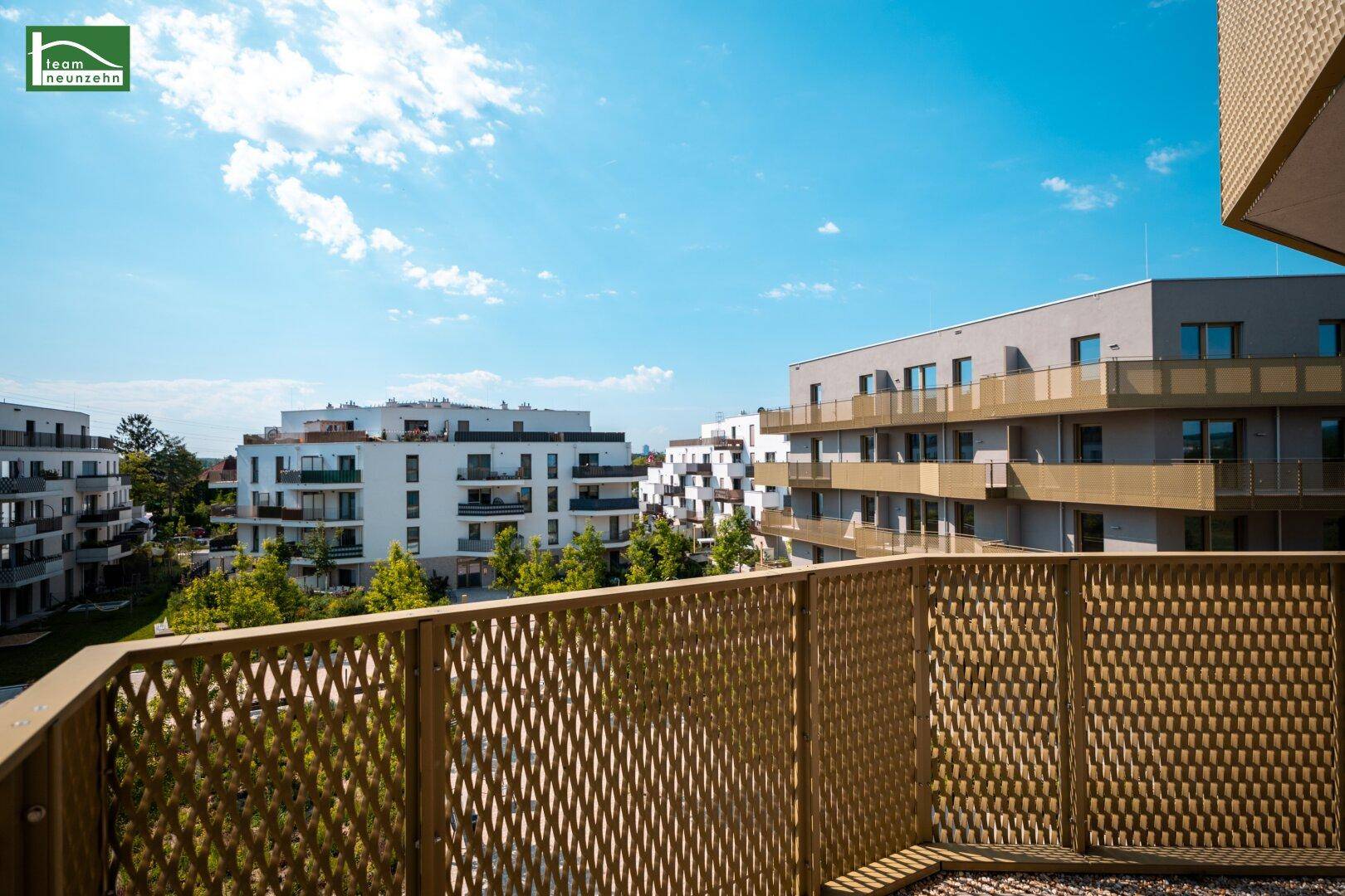 Sonniger Balkon mit Gitterbrüstung und weitem Blick über die grüne Umgebung.