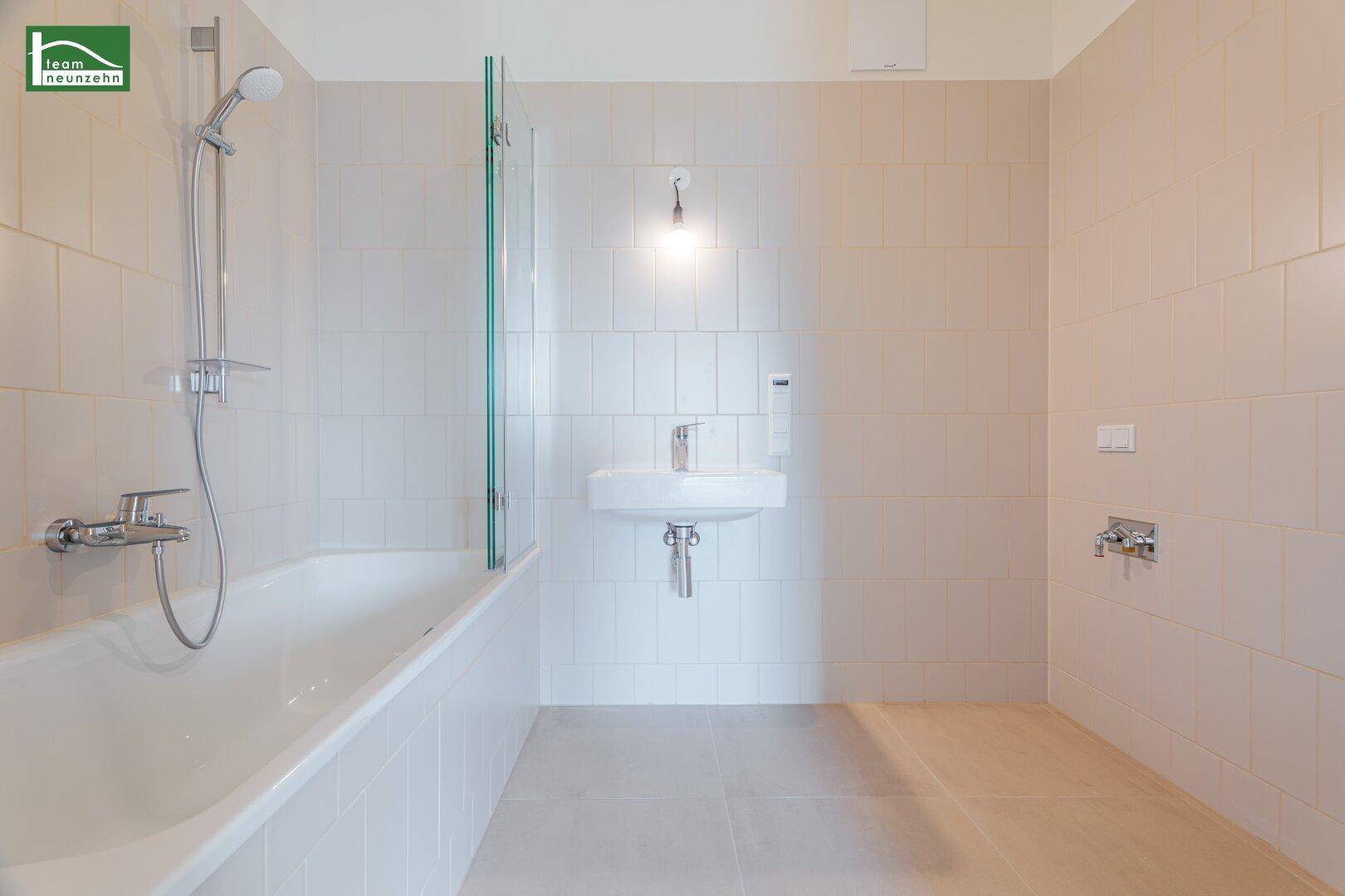 Helles Badezimmer mit Badewanne, Duscharmatur und modernem Waschbecken.