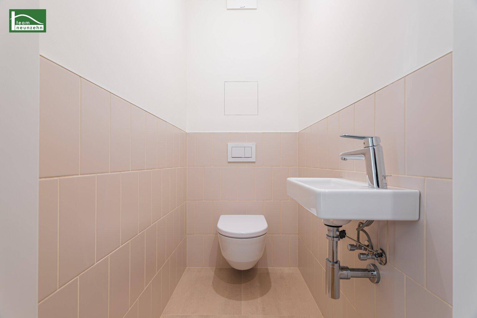 Modernes Gäste-WC mit beigefarbenen Fliesen, wandhängendem WC und Einzelwaschbecken.