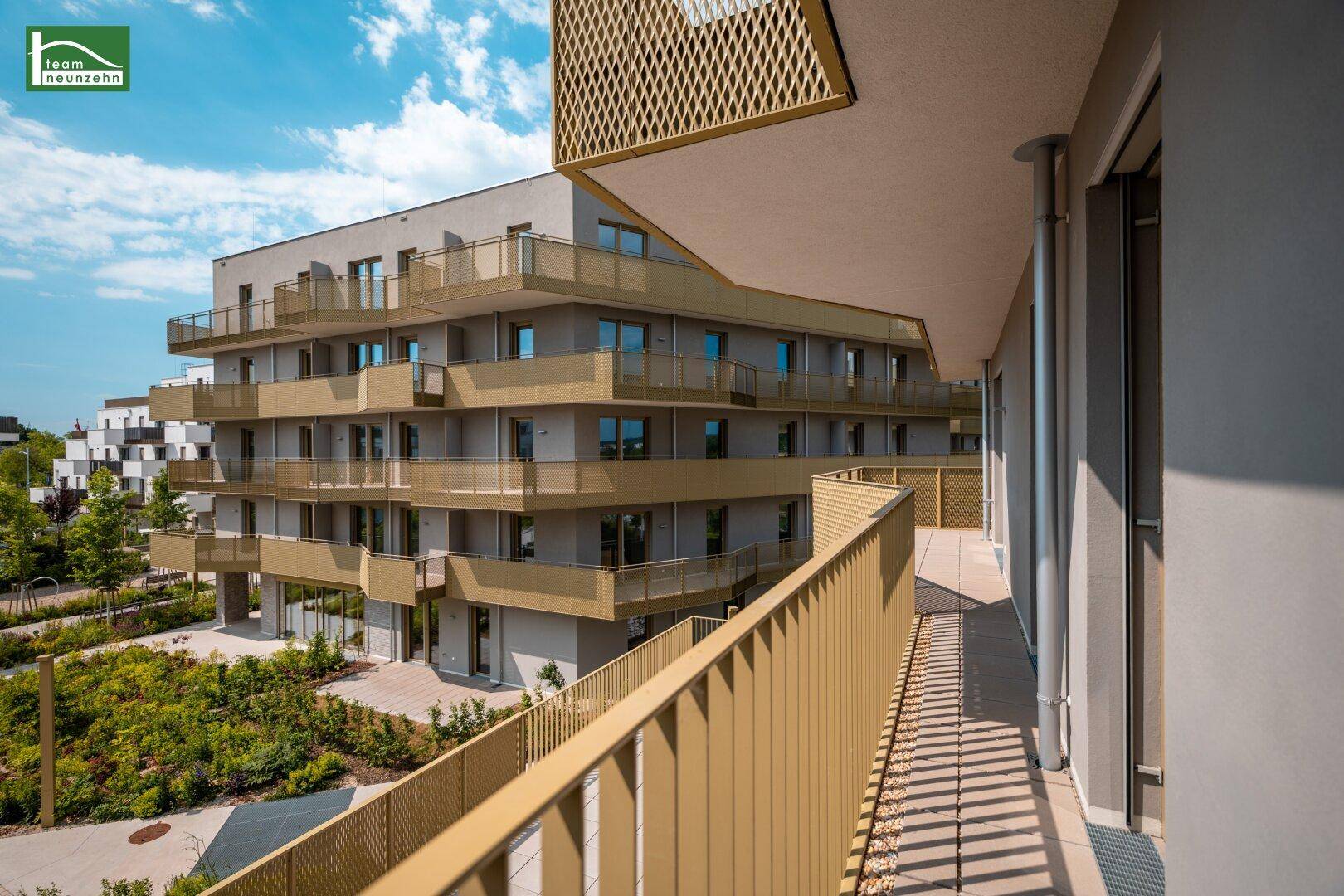 Großer Balkon mit modernem Metallgeländer und Blick auf die Wohnanlage.