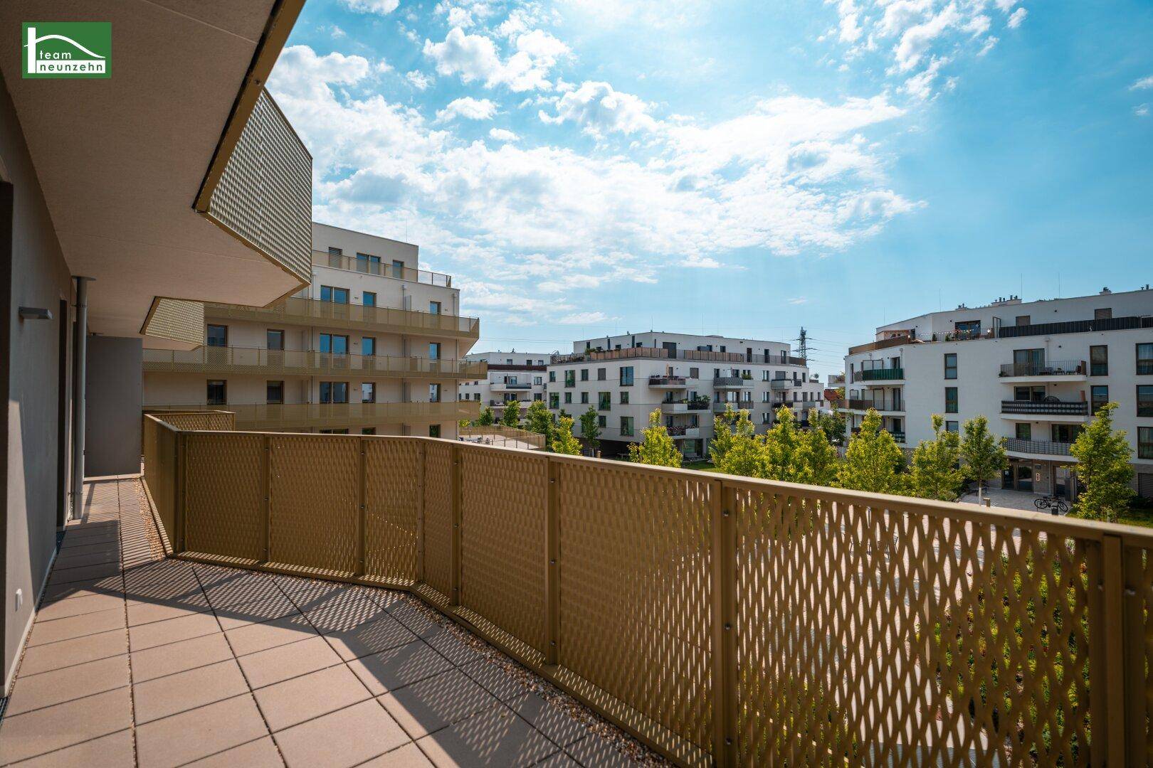 Geräumiger Balkon mit Fliesenboden und weitem Blick über die Wohnanlage.