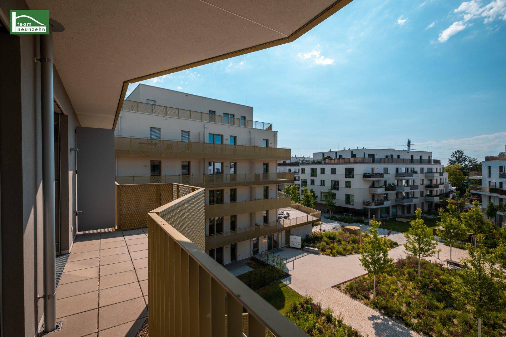 Geräumiger Balkon mit Fliesenboden und Blick auf die moderne Wohnanlage.