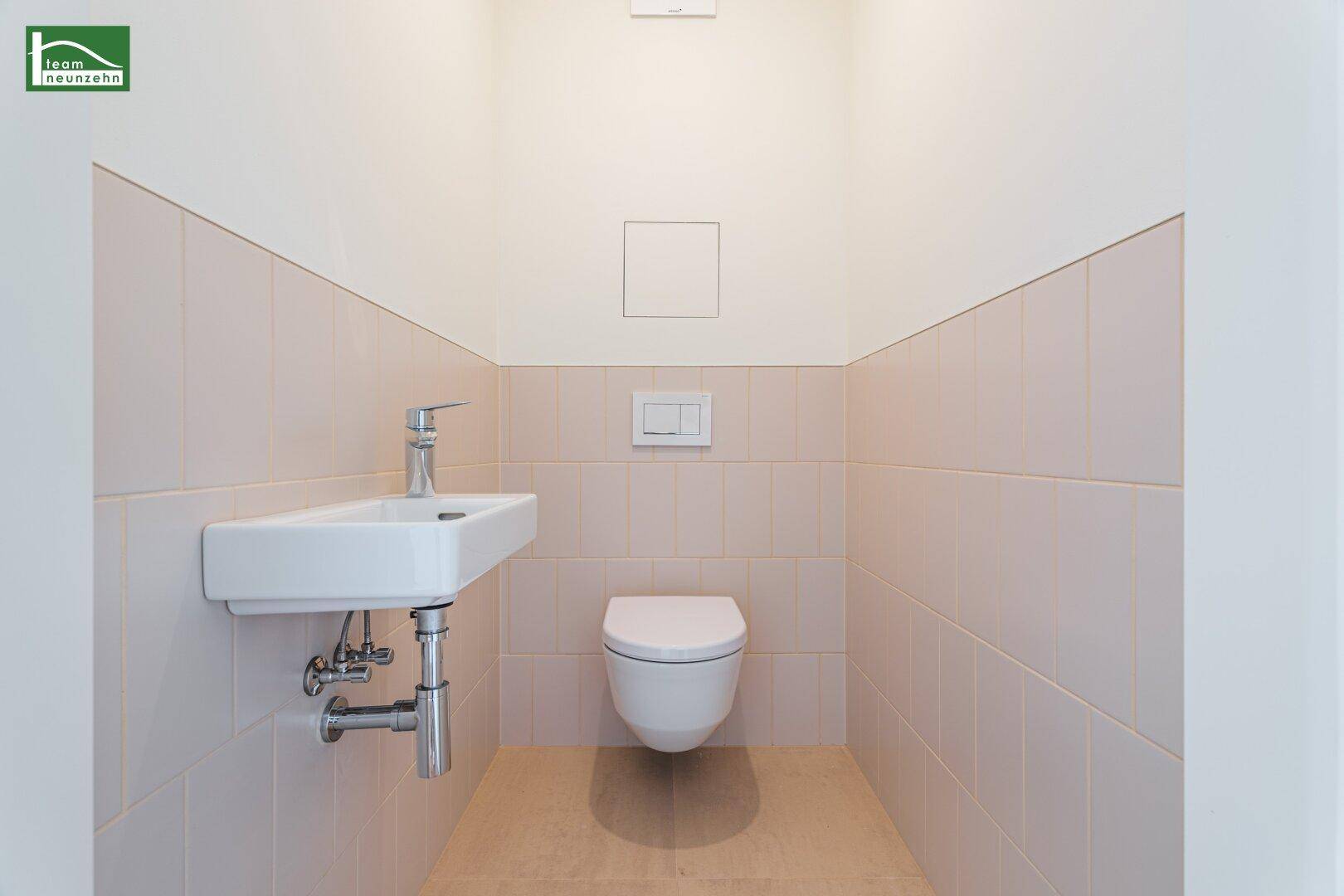 Separates WC mit wandhängender Toilette und kleinem Waschbecken.