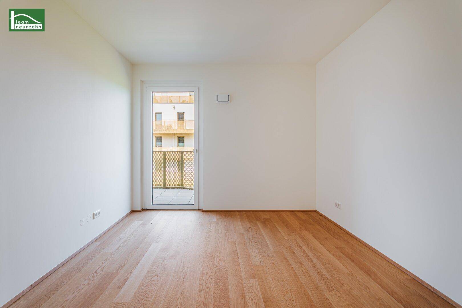 Helles Zimmer mit Holzboden und Zugang zu einem französischen Balkon, ideal als Schlafzimmer.