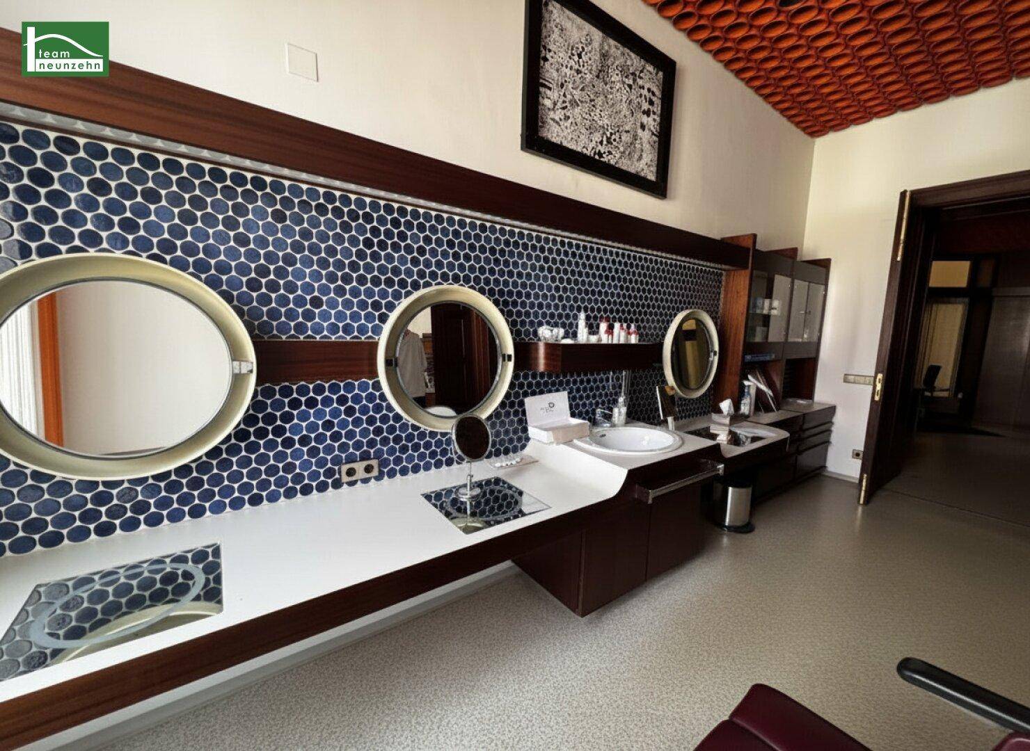 Stilvolles Badezimmer mit mehreren Waschbecken, runden Spiegeln und blauen Mosaikfliesen an der Wand.