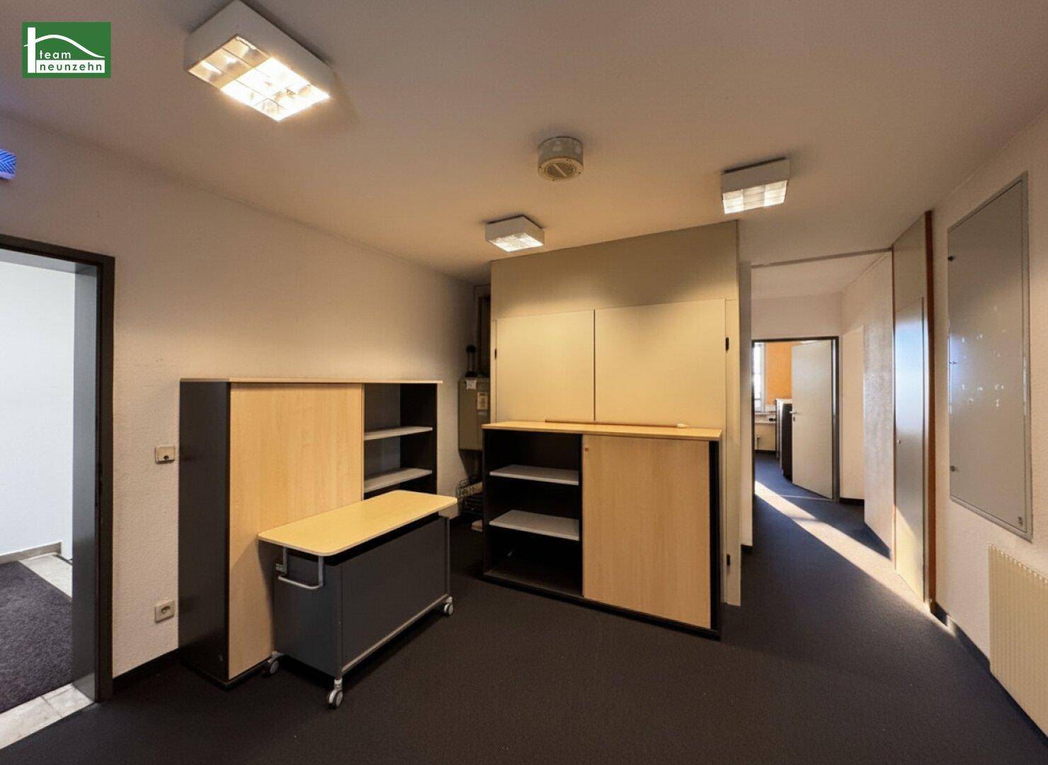 Bürogang mit Schränken und einem mobilen Rollcontainer, führt zu weiteren Räumen.