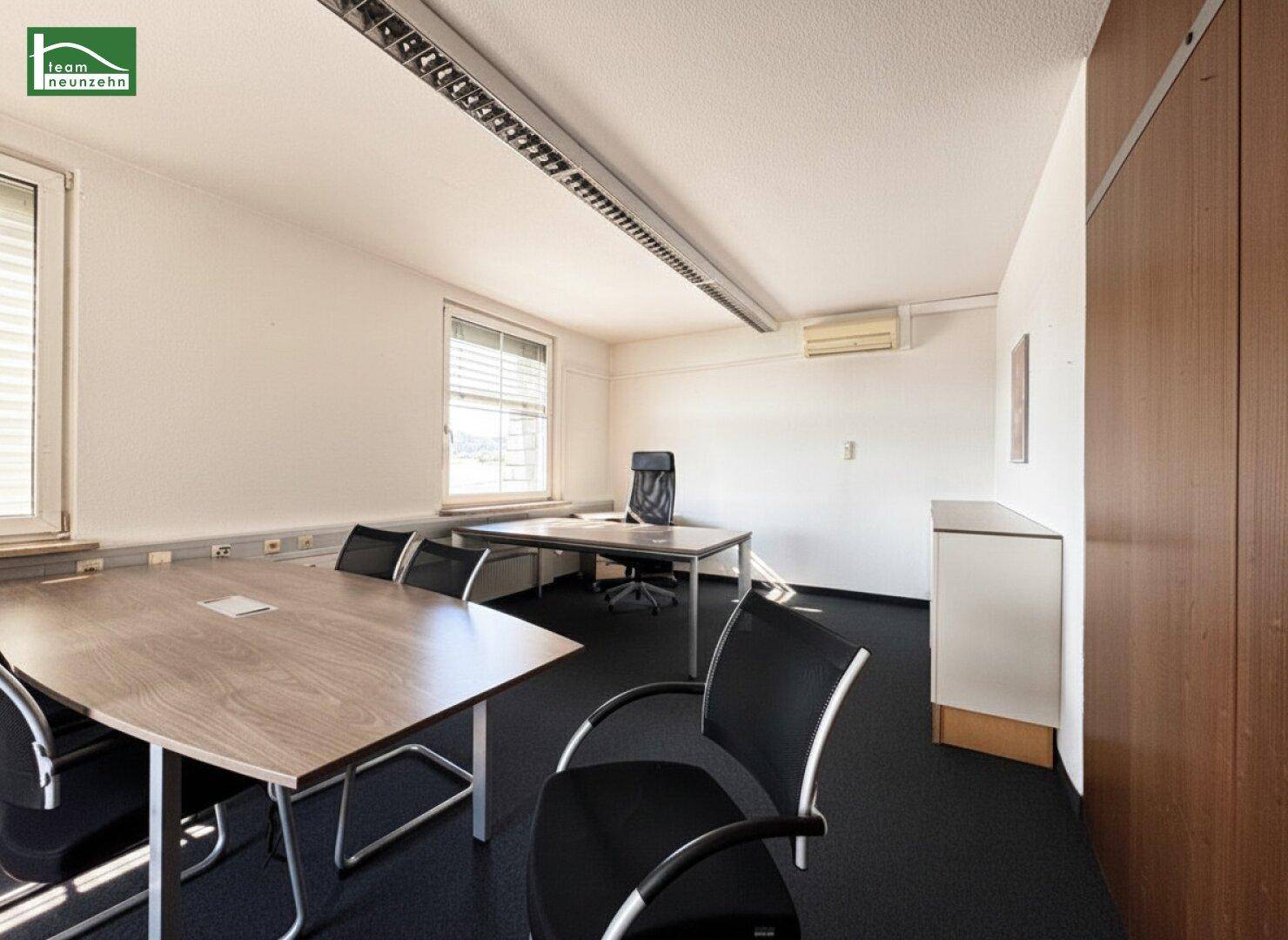 Besprechungsraum oder Einzelbüro mit großem Tisch, Stühlen und Fensterblick.