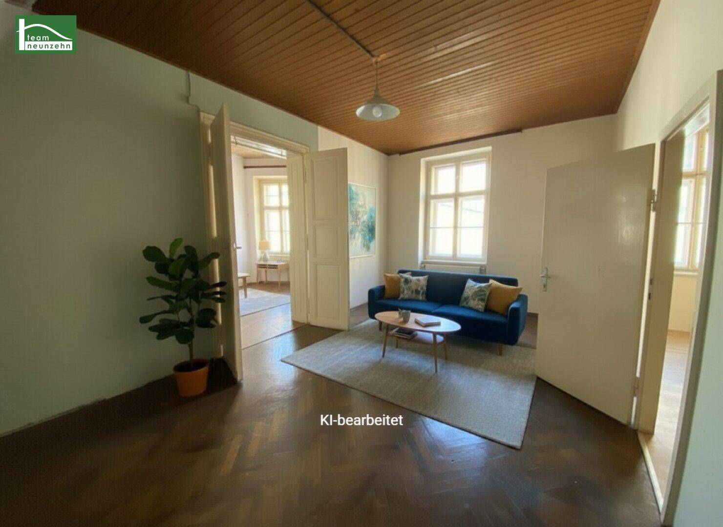 Gemütliches Wohnzimmer mit Fischgrätparkett, hohen Decken und einem blauen Sofa.