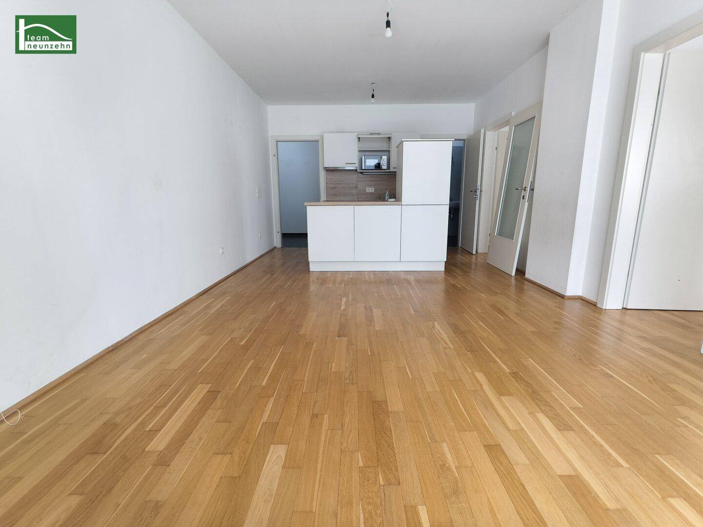 Offener Wohnbereich mit Parkettboden und integrierter Küchenzeile in modernem Design.