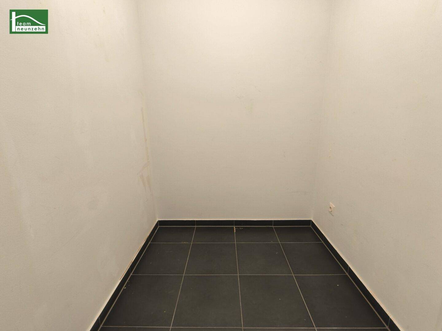 Kleiner Abstellraum mit dunklen Fliesen, ideal für zusätzlichen Stauraum.