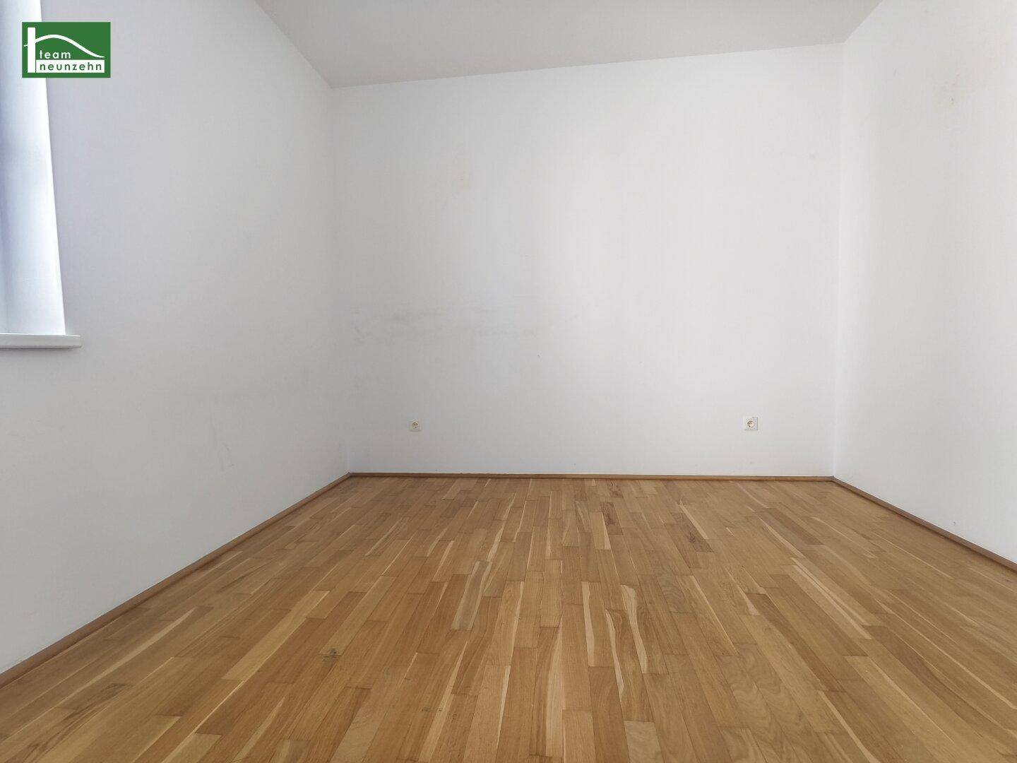 Geräumiges, leeres Zimmer mit Parkettboden und weißen Wänden, ideal als Schlafzimmer.
