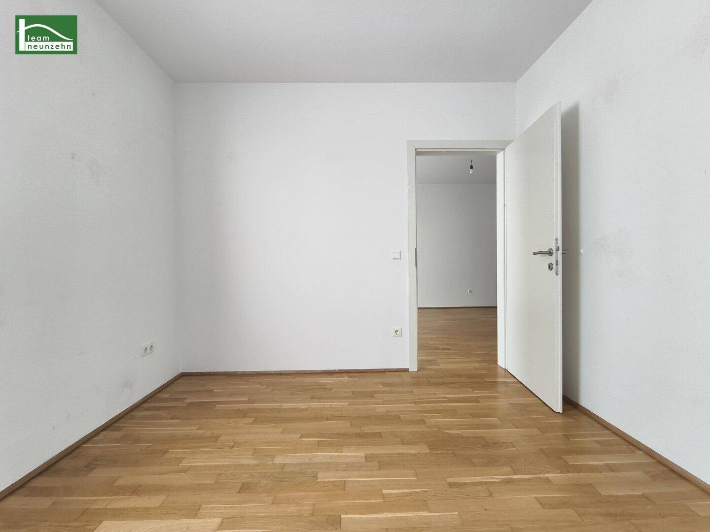 Leeres Zimmer mit Parkettboden und weiß gestrichenen Wänden, bereit zur individuellen Gestaltung.