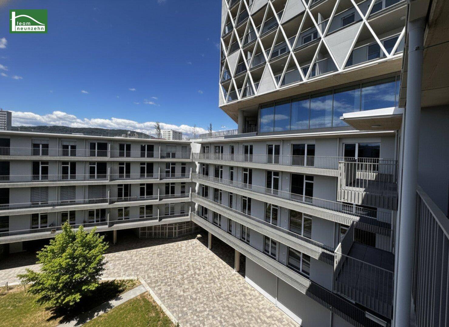 Blick auf den Innenhof des modernen Wohnkomplexes mit mehreren Gebäudeteilen und Balkonen.