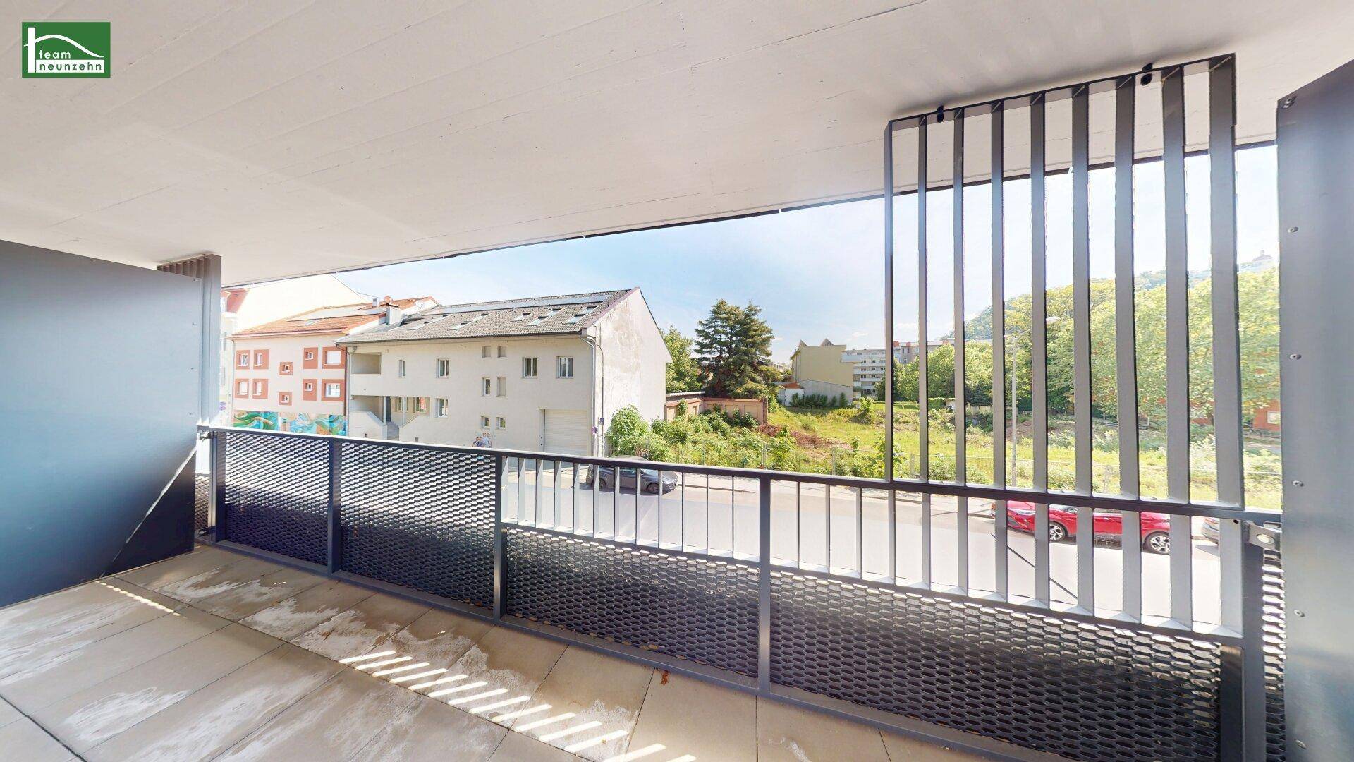 Geräumiger Balkon mit moderner Metallbrüstung und Blick auf die umliegenden Gebäude und Grünflächen.