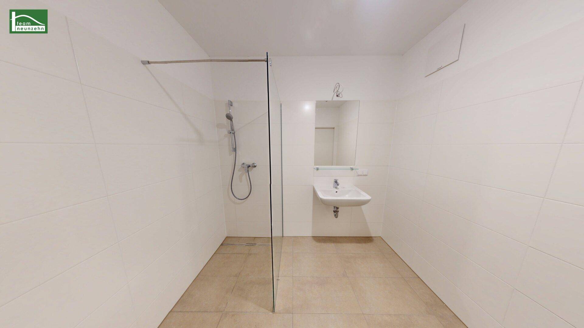 Modernes Badezimmer mit großer begehbarer Dusche und weiß gefliesten Wänden.