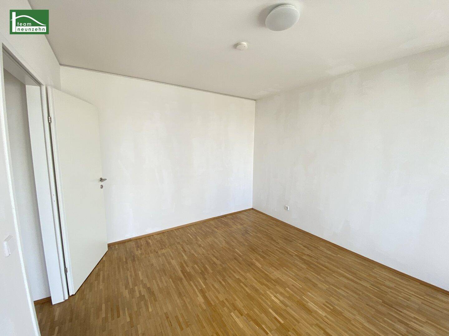 Leeres Schlafzimmer mit Holzboden und weiß gestrichenen Wänden, bereit zur Einrichtung.
