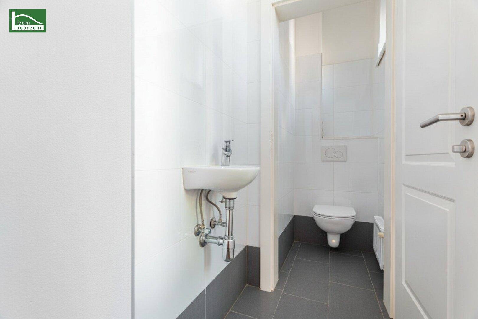 Kompaktes Gäste-WC mit wandhängender Toilette und kleinem Handwaschbecken in modernem Design.