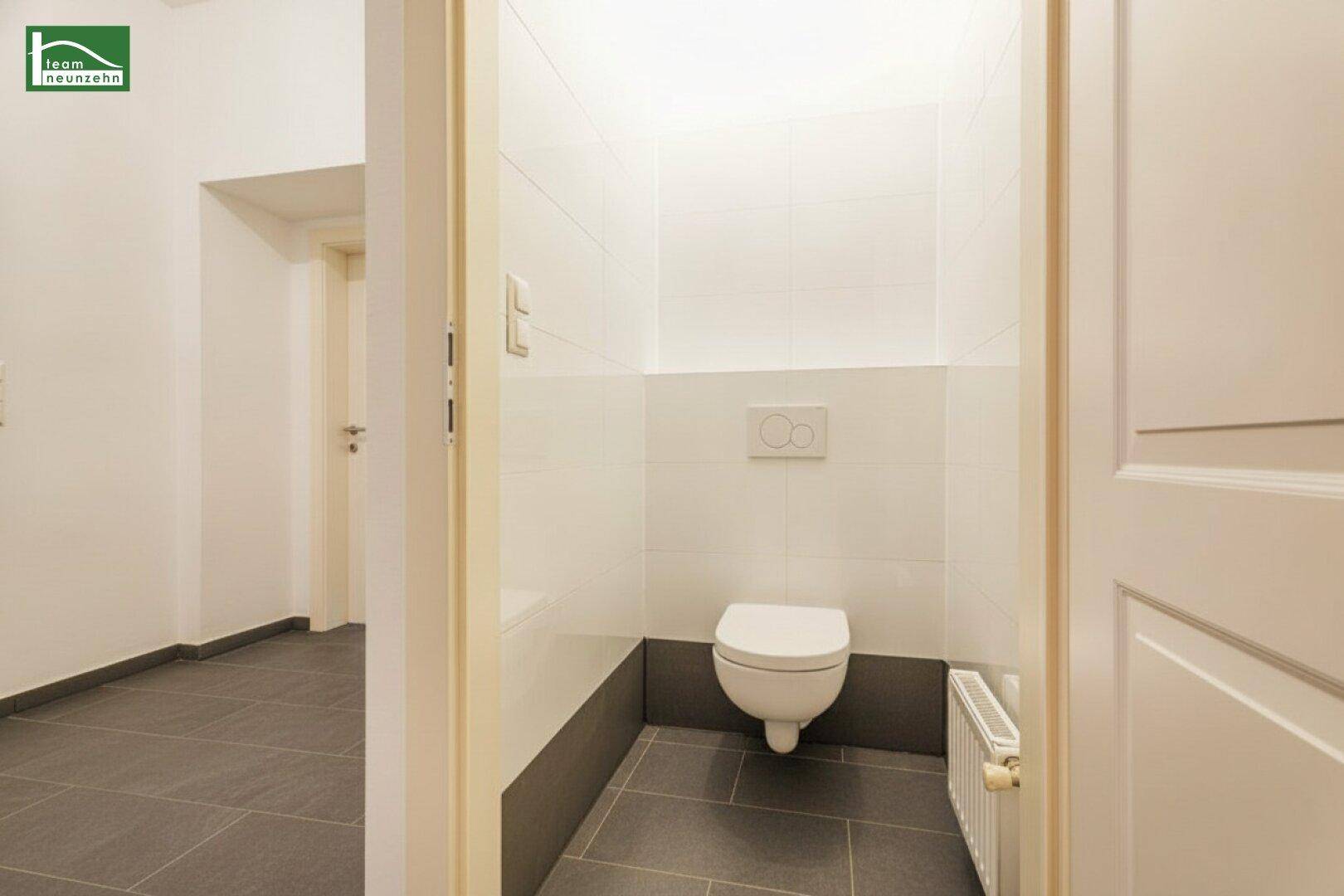 Modernes Gäste-WC mit Wand-WC, Fliesenboden und Heizkörper in einem gepflegten Zustand.