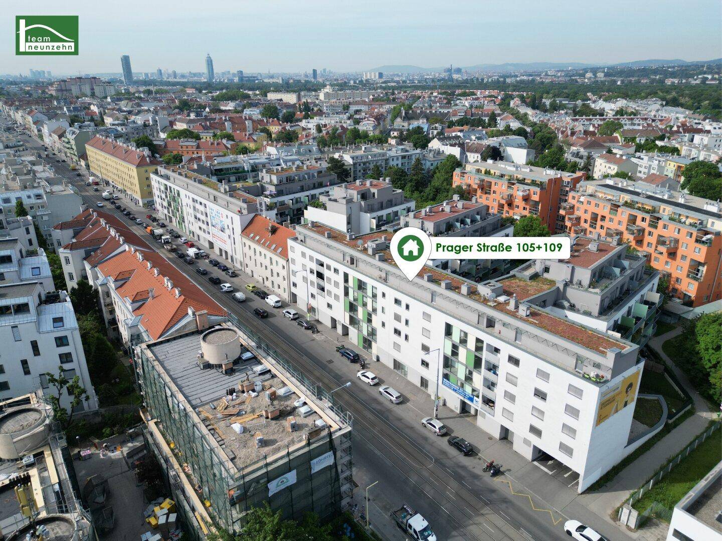 Luftaufnahme einer städtischen Wohngegend mit einem markierten modernen Gebäude und viel Grün.